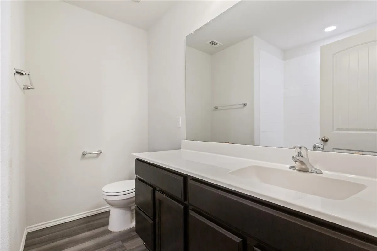 Vanity with a white integrated sink and countertop, dark wood-finish cabinetry, and chrome fixtures