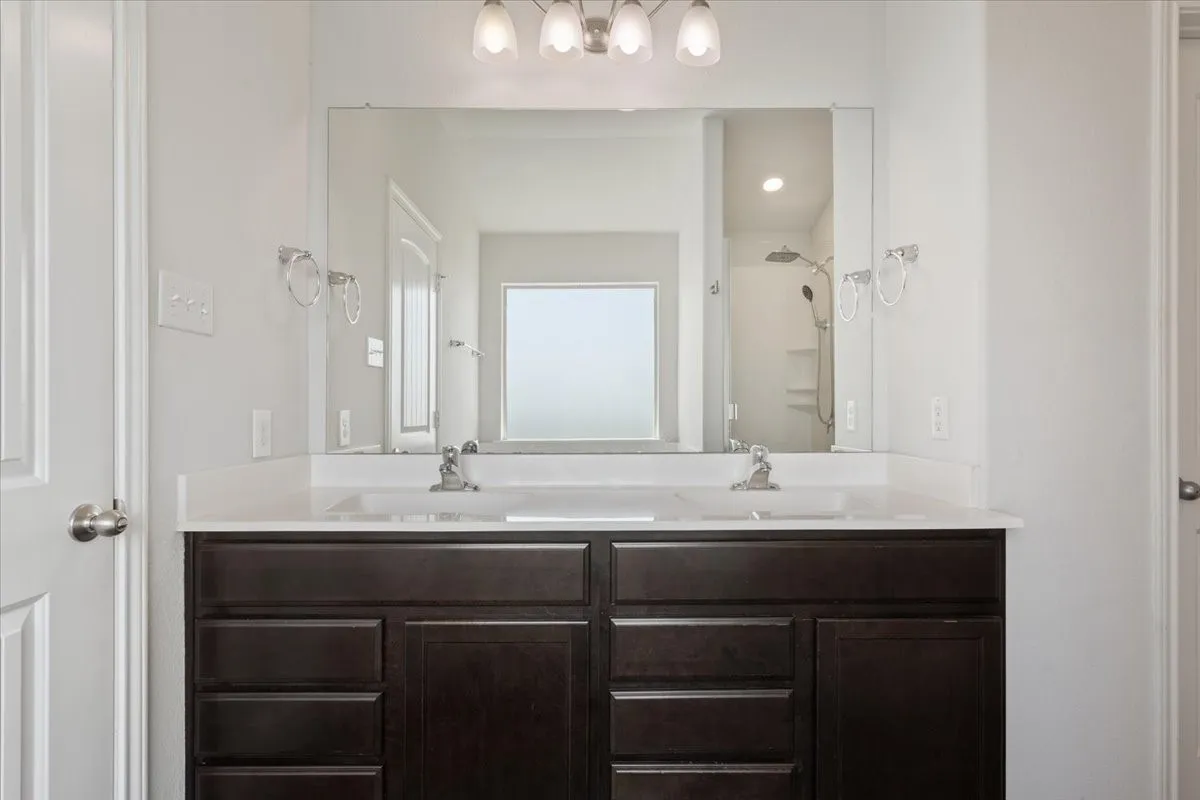 Double vanity with dark wood-finish cabinetry, integrated sinks, and polished chrome faucets