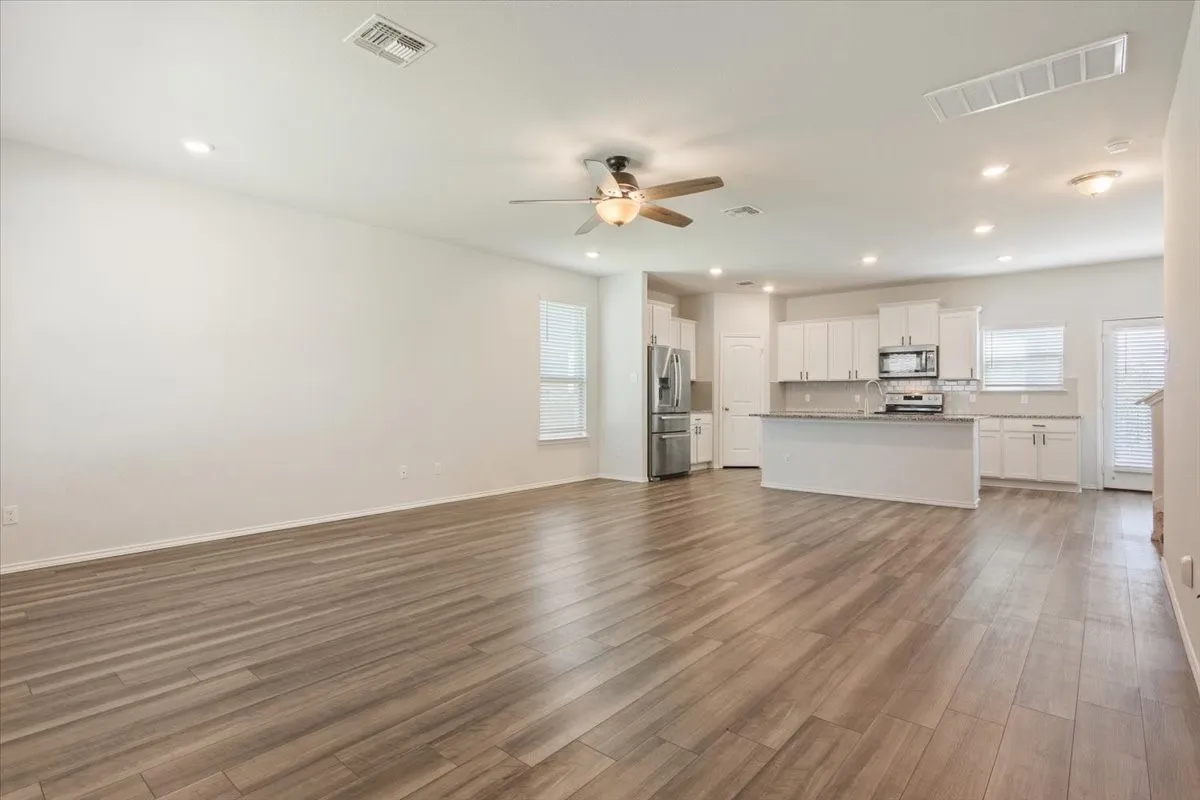 Expansive main living area featuring wood-finish flooring, recessed lighting, and a ceiling fan