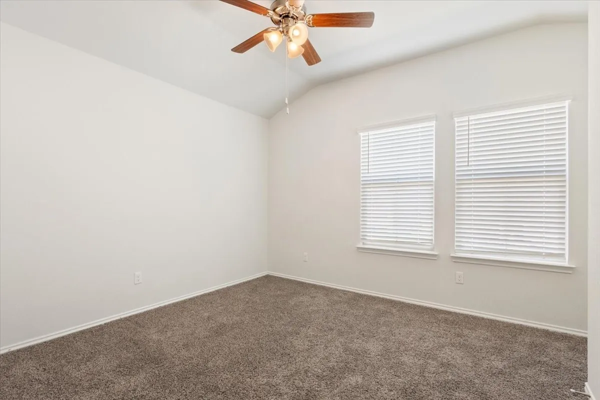 Room featuring vaulted ceiling, neutral wall paint, and brown carpet flooring