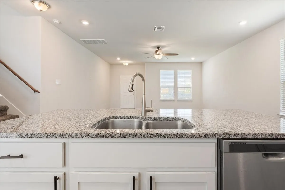 Kitchen island featuring a dual basin stainless steel sink with a pull-down faucet and granite countertop