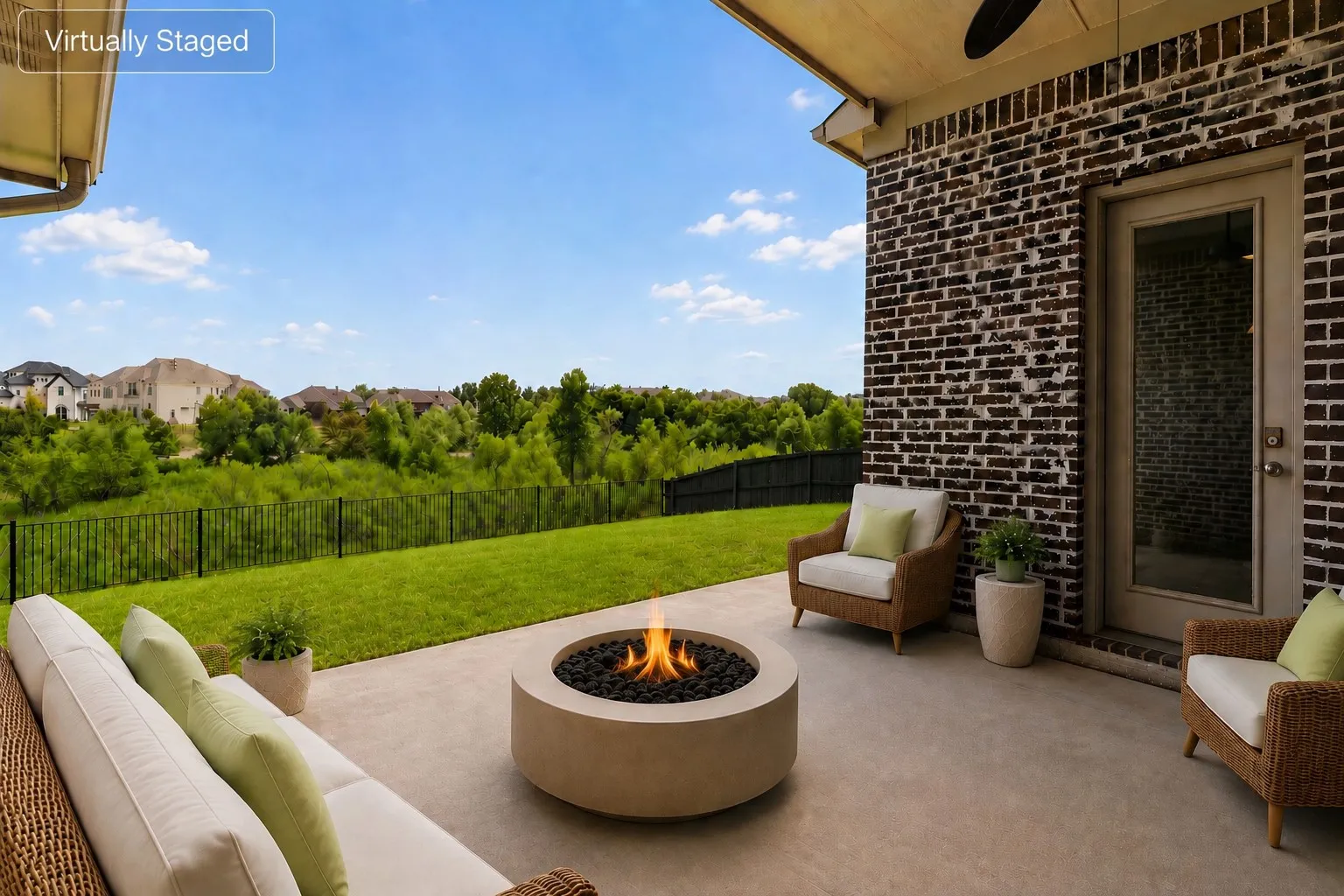 Covered outdoor patio featuring a concrete fire pit, dark brick exterior, and a glass-paneled door