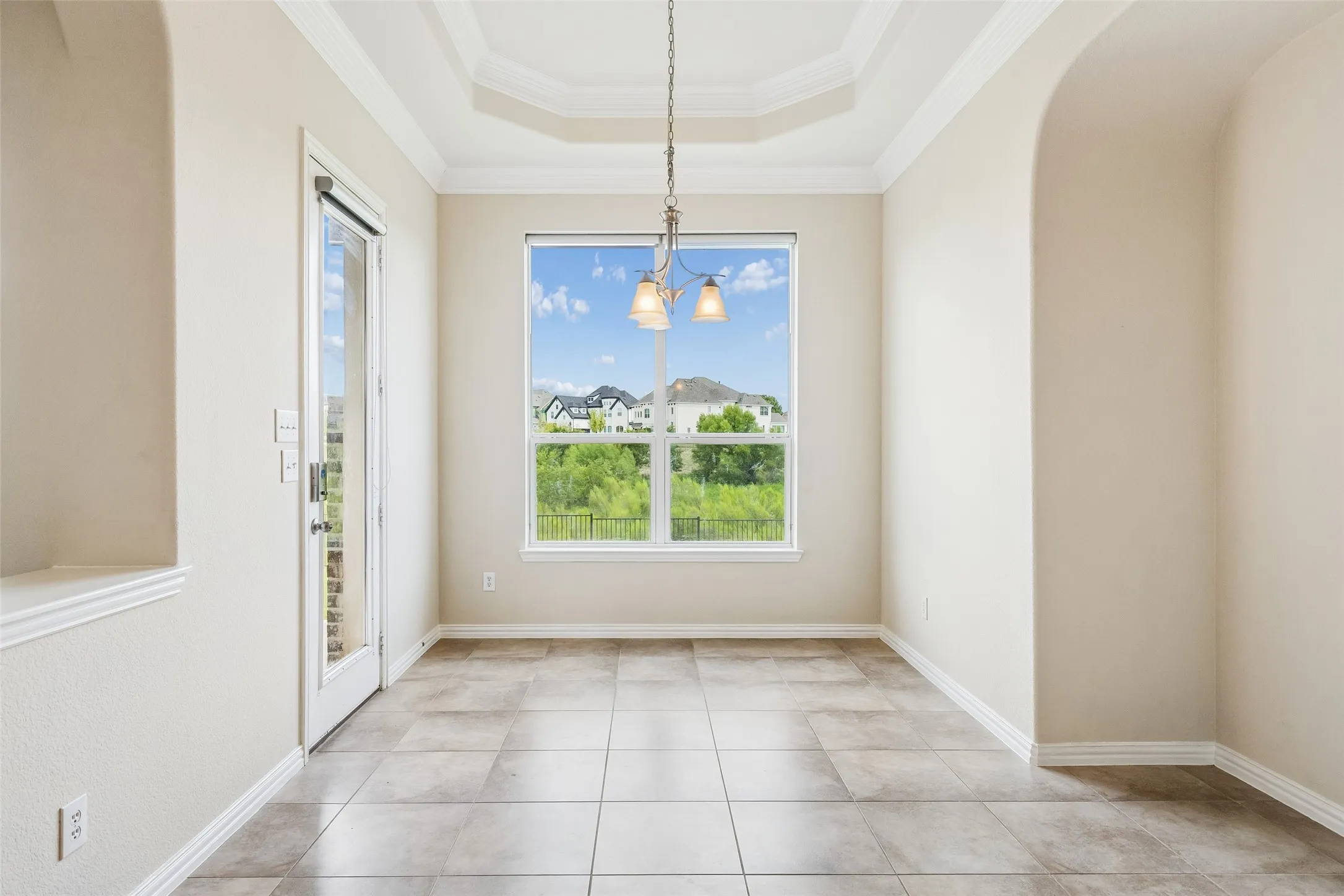 Dining area featuring a tray ceiling, a multi-light chandelier, and large window with exterior scenery