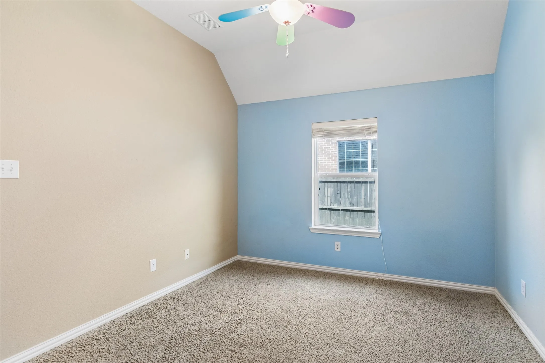 Carpeted room featuring a single window with blinds, a vaulted ceiling, and a ceiling fan