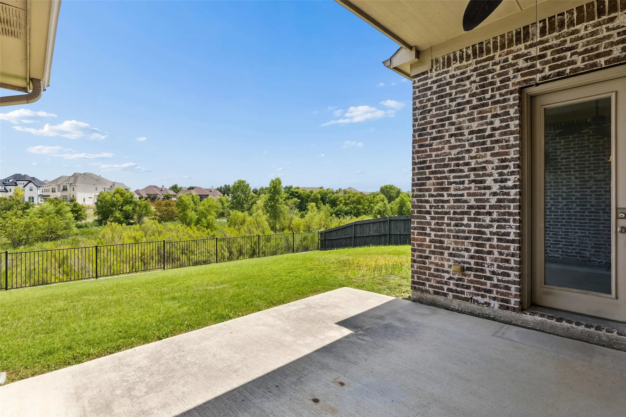 Covered patio with a concrete slab, brick exterior wall, and an exterior door with glass insert
