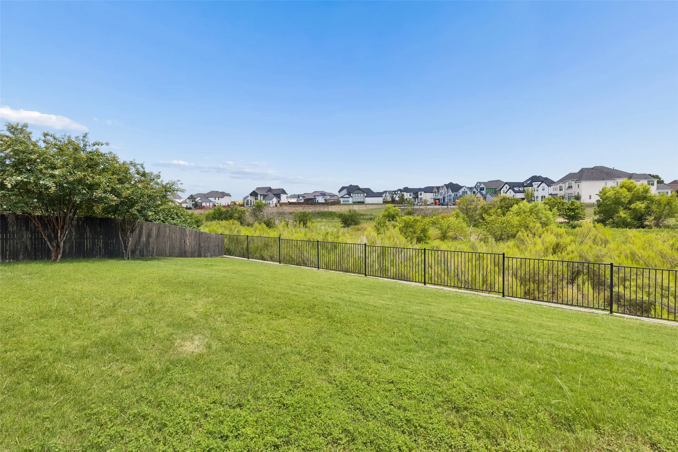 Expansive backyard featuring a manicured lawn, a mature tree, and a dark wood privacy fence