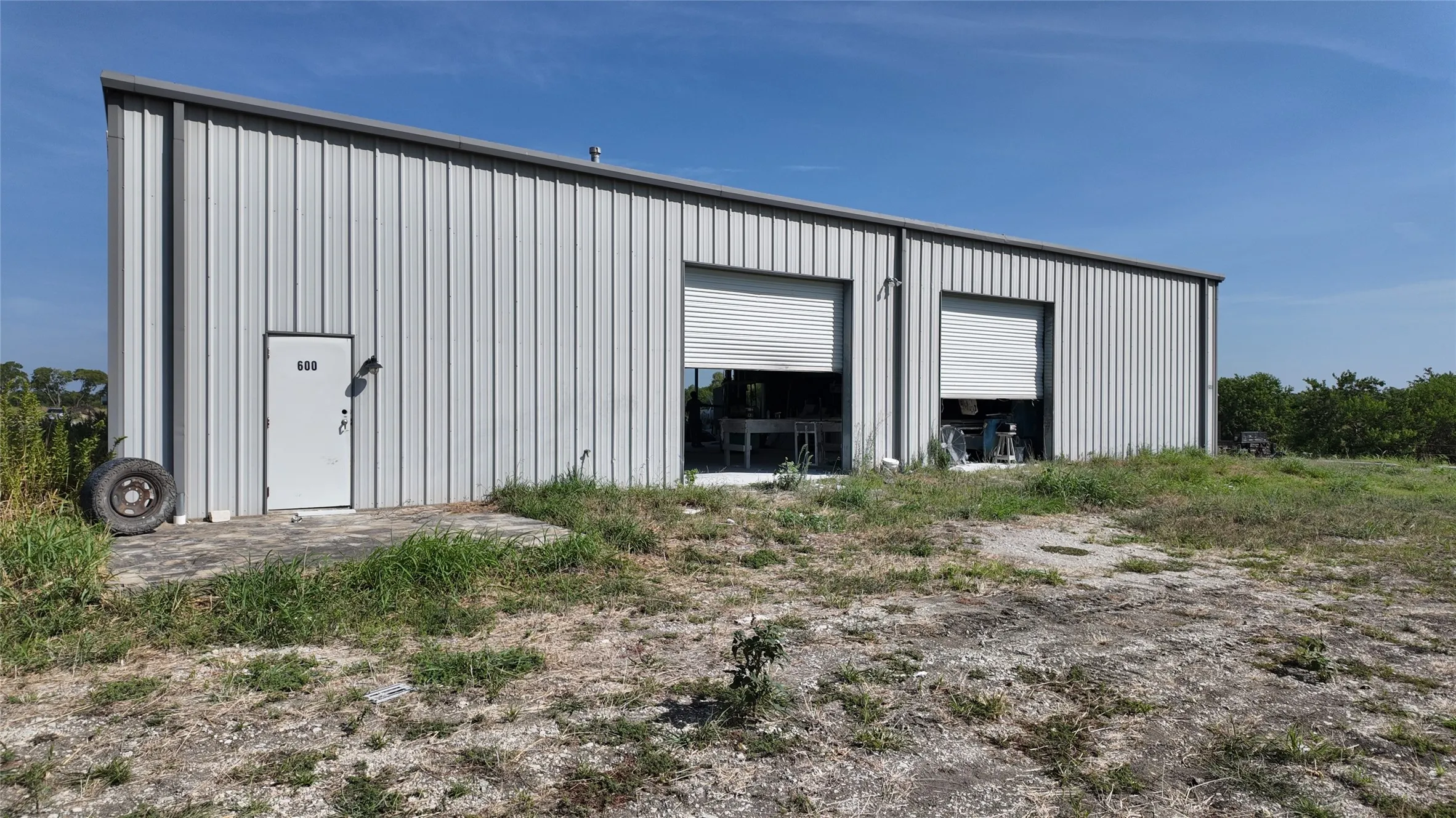 Metal-sided industrial building featuring a sloped roofline and two large roll-up doors