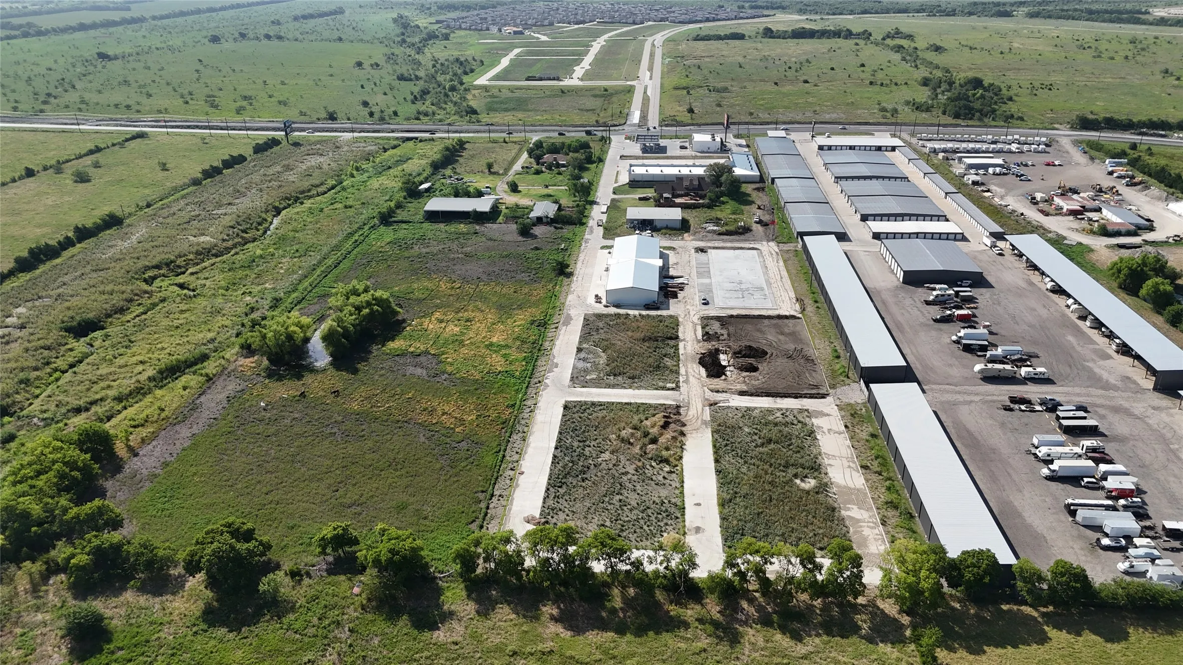 Expansive commercial property featuring multiple industrial buildings, extensive paved parking areas, and open land space