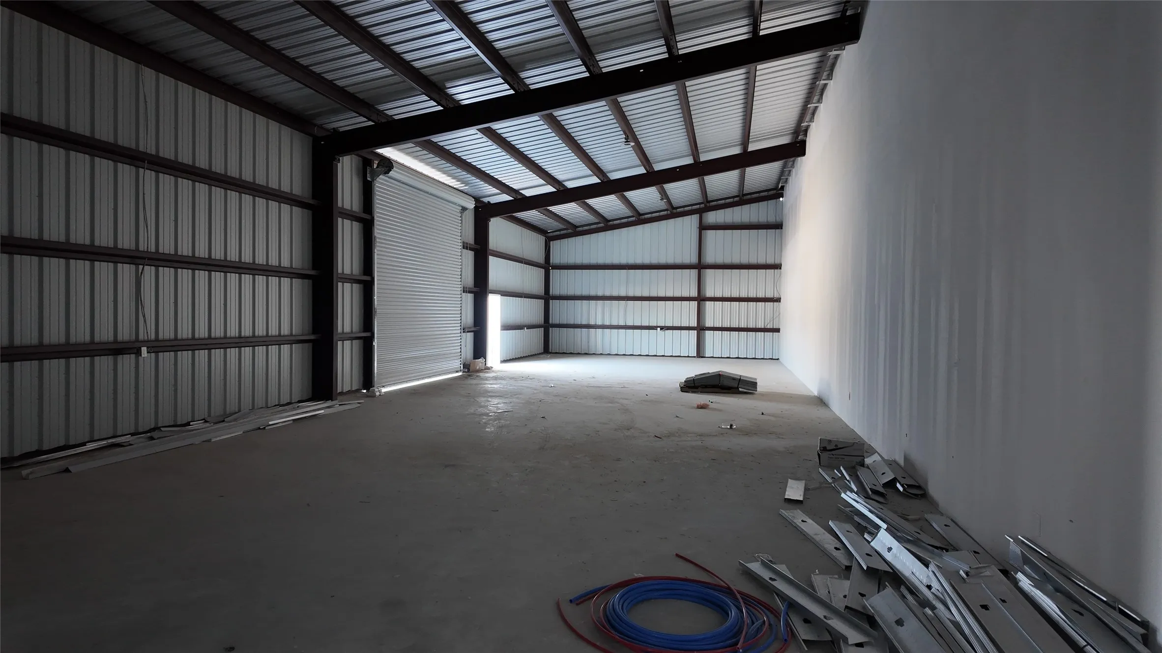 Spacious industrial interior featuring a concrete floor and a metal roll-up door