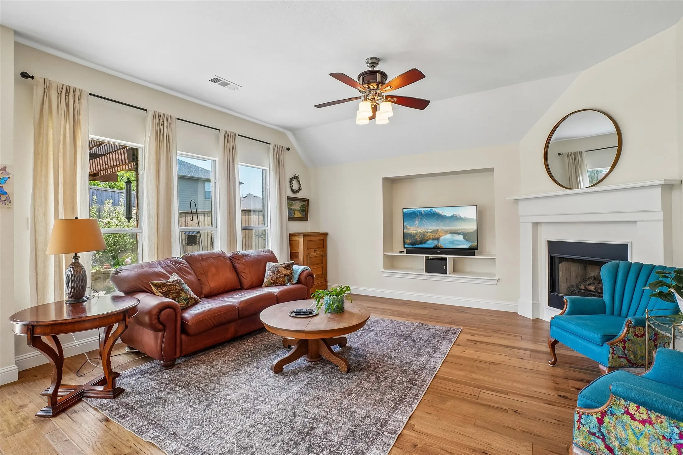 Spacious and open family room with a wall of windows looking out to the landscaped backyard. Fireplace with gas logs.  Updated ceiling fan and engineered hickory wood floors.