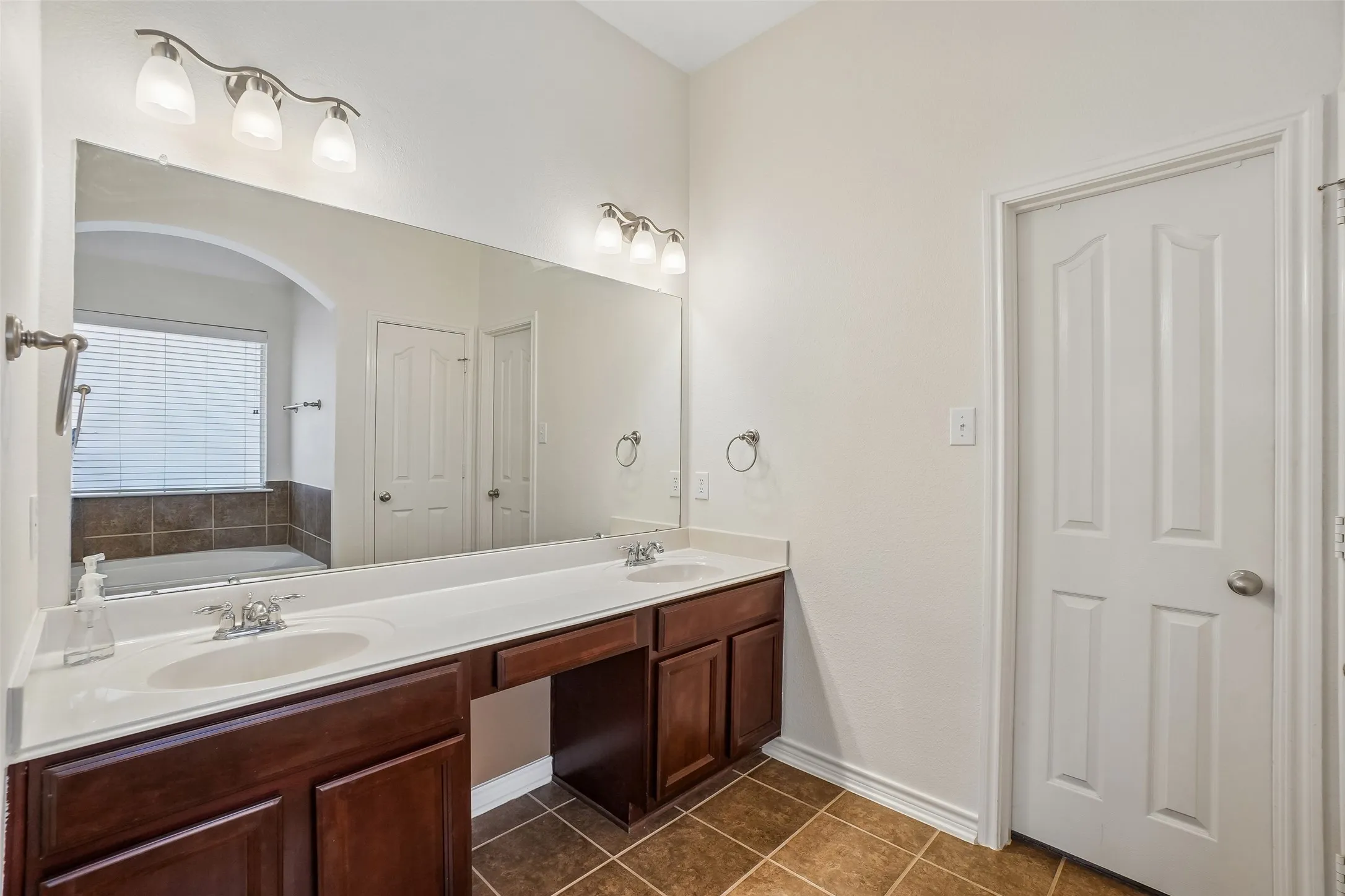 Two sinks, tile floors, makeup area, and a walk in closet in the primary bathroom.