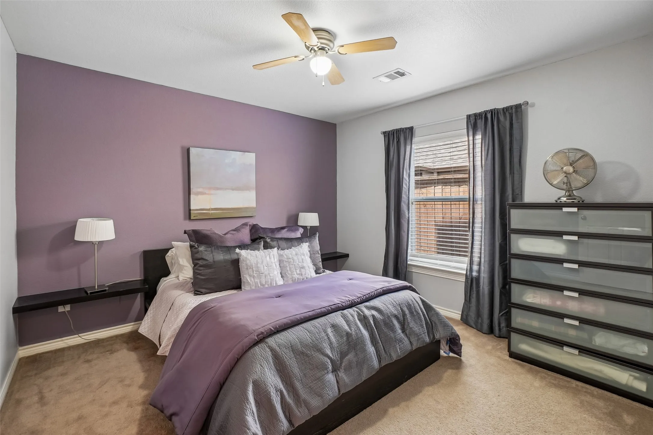 One of the secondary bedrooms with carpet and a ceiling fan.  The shelves on either side of the bed are excluded from the sale.