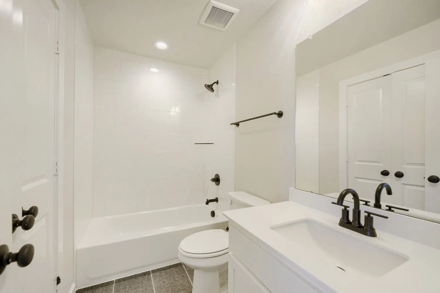 Bright and clean bathroom featuring dual vanities with white quartz countertops, matte black hardware and faucets, and an undermount sink