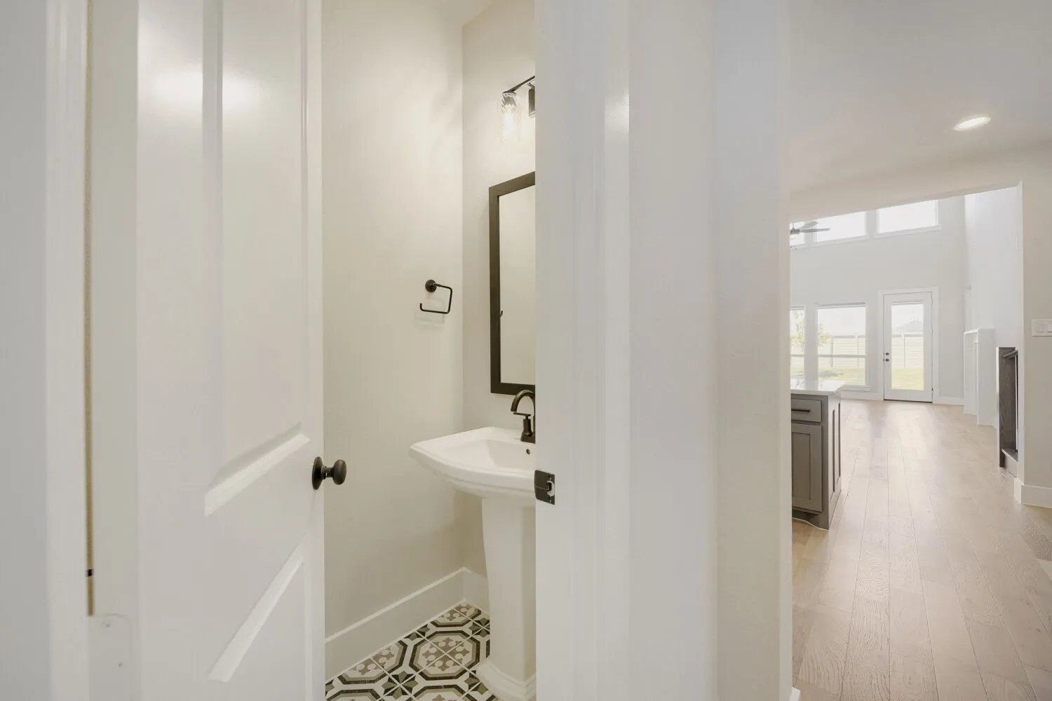 Pedestal sink with dark-framed mirror and wall-mounted light fixture