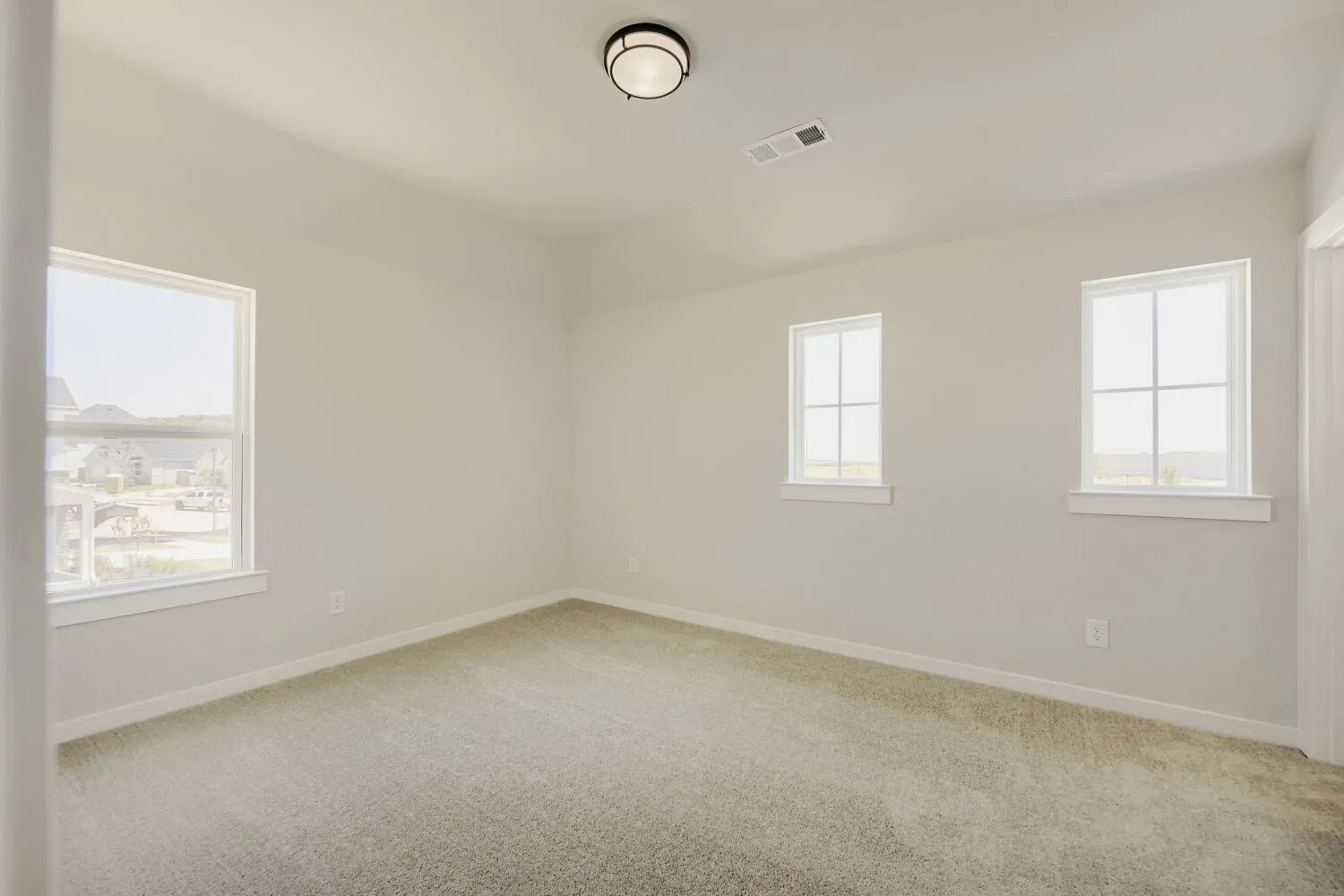 Carpeted room featuring light-colored walls and multiple windows with white trim