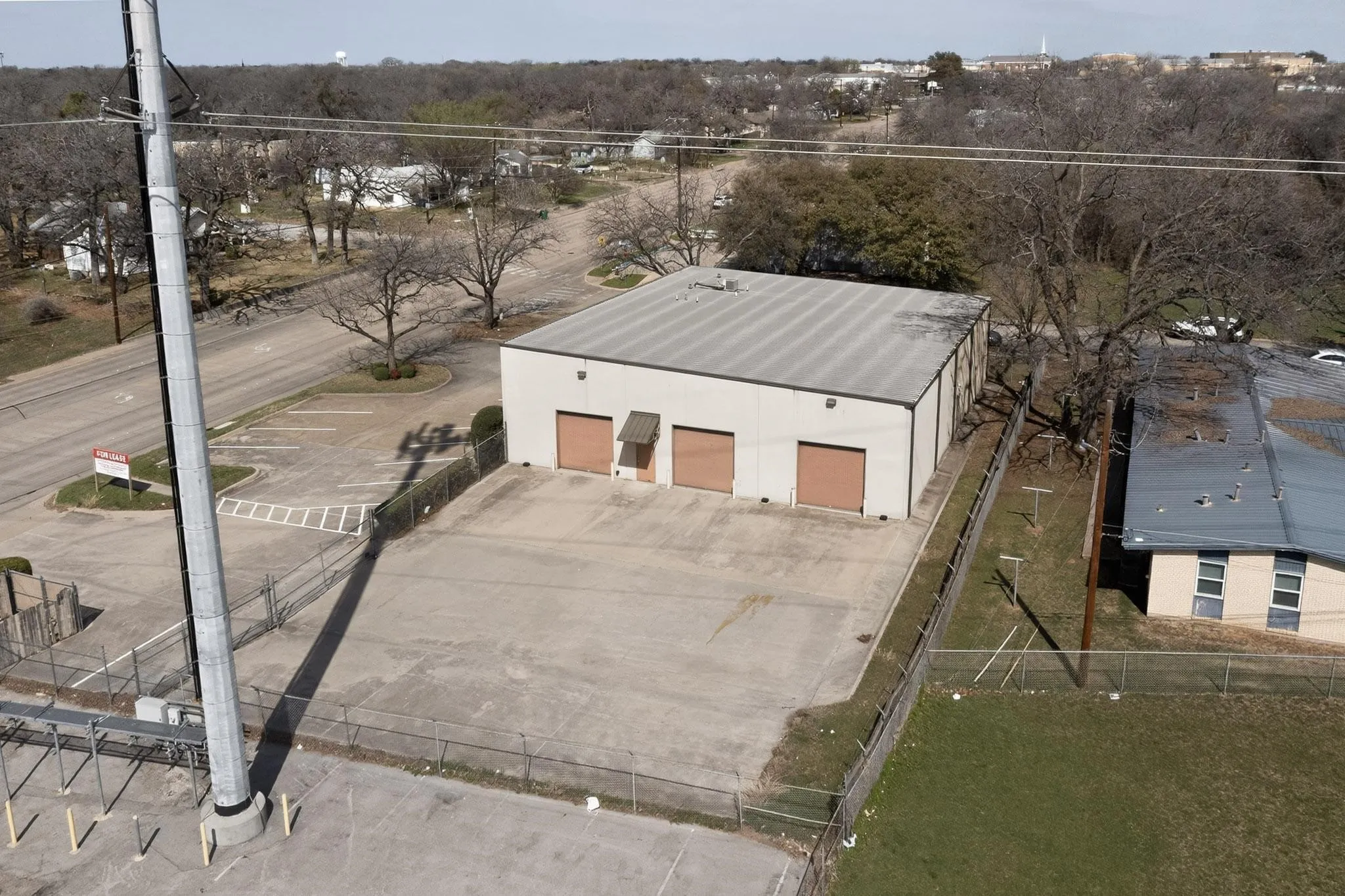 Industrial building with three roll-up doors, a flat roof, and a fenced perimeter