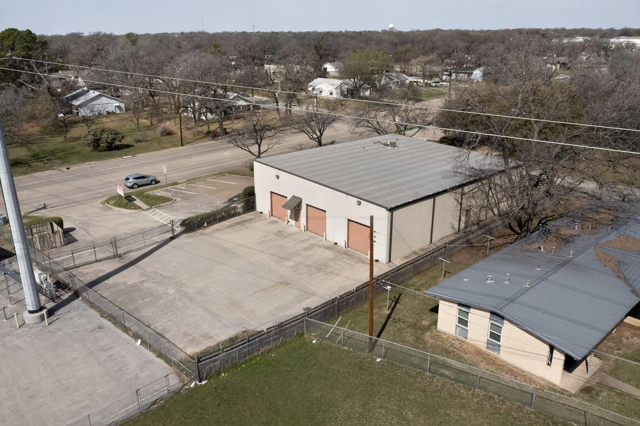 Commercial building with a metal roof, three roll-up doors, and an expansive paved lot