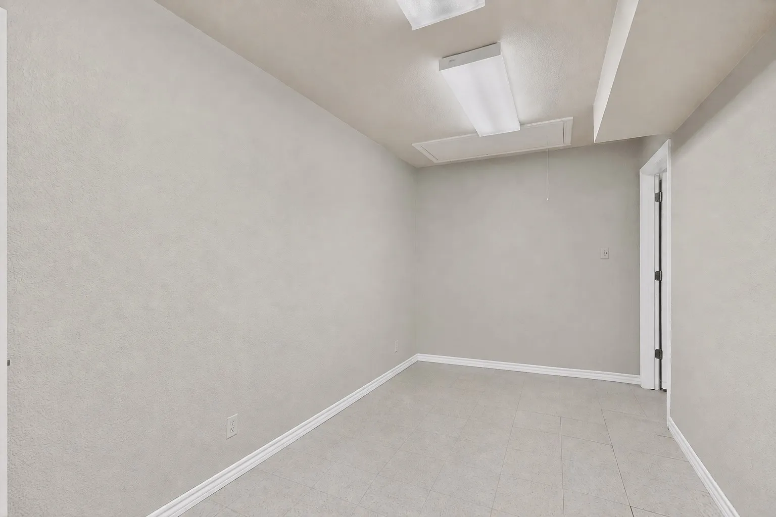 Recessed ceiling lighting, tiled flooring, white baseboards, and a white interior door with dark hardware