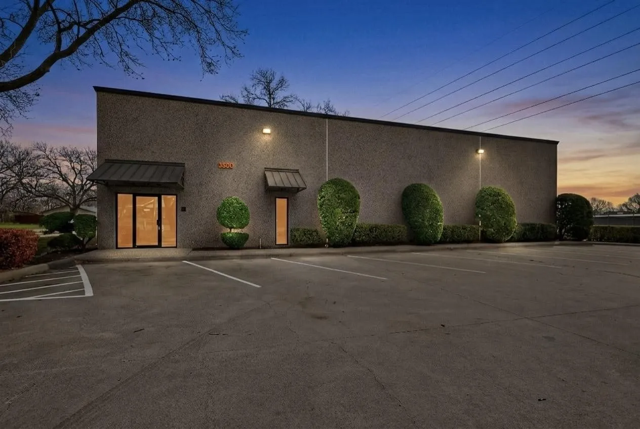Exterior featuring a textured facade, multiple awnings, and landscaped shrubbery