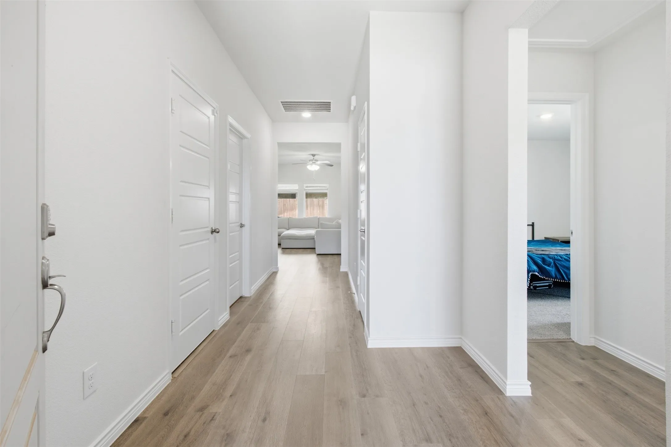 Hallway with neutral tone walls and wood-finish flooring