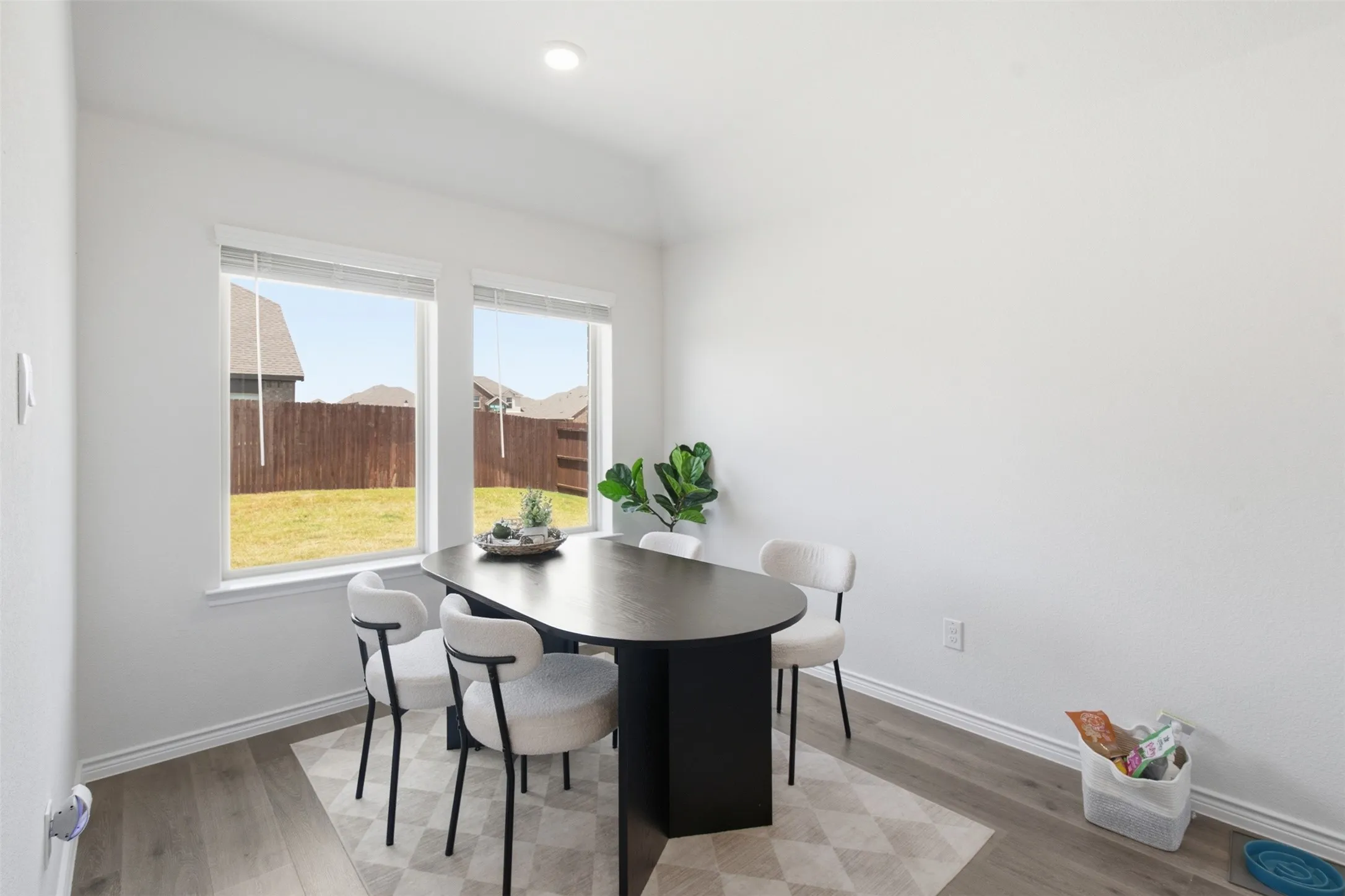 Bright room featuring wood-finish flooring, two large windows, and a recessed ceiling light
