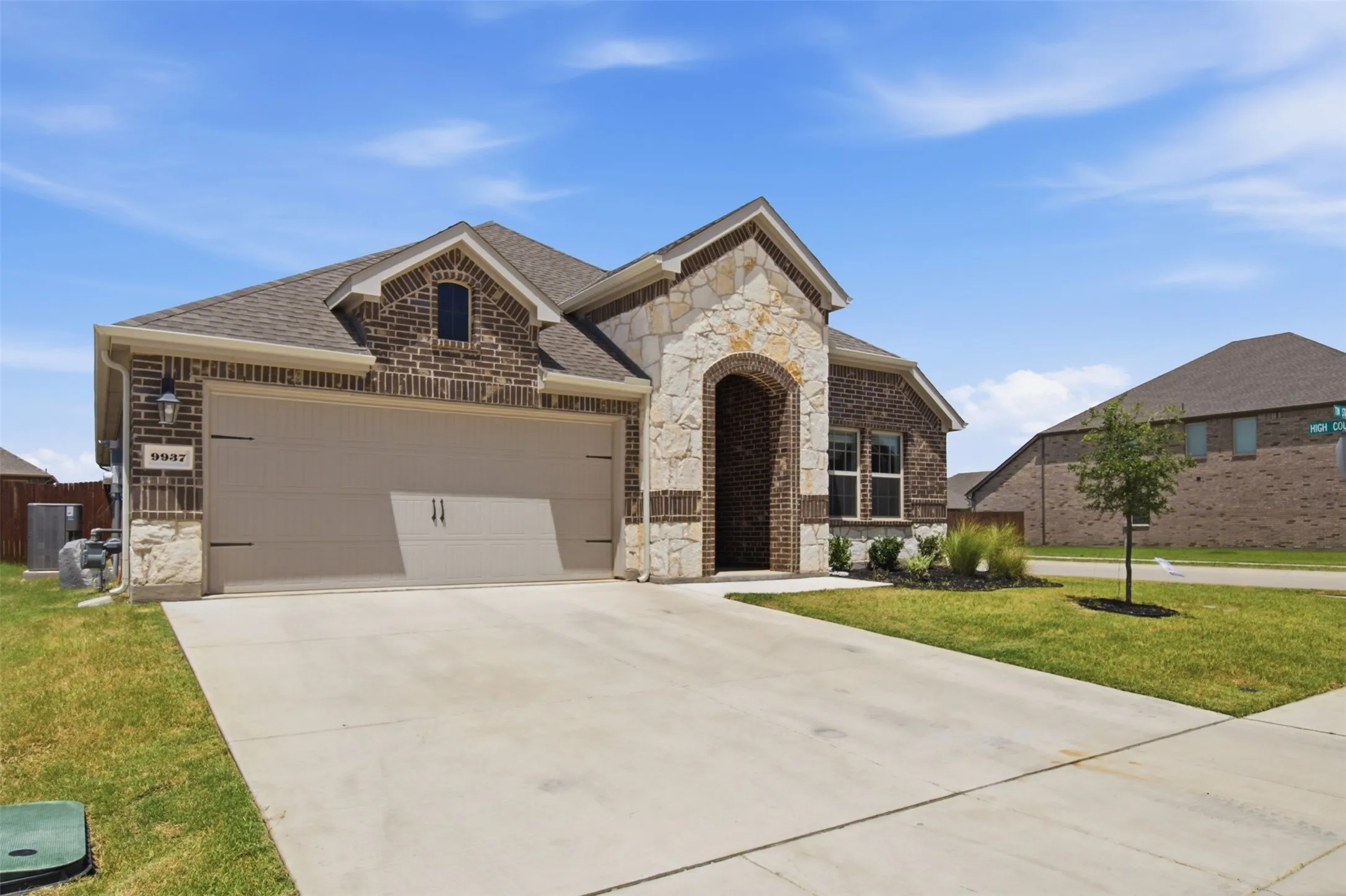 Brick and stone facade featuring an arched entry, a two-car garage, and a concrete driveway