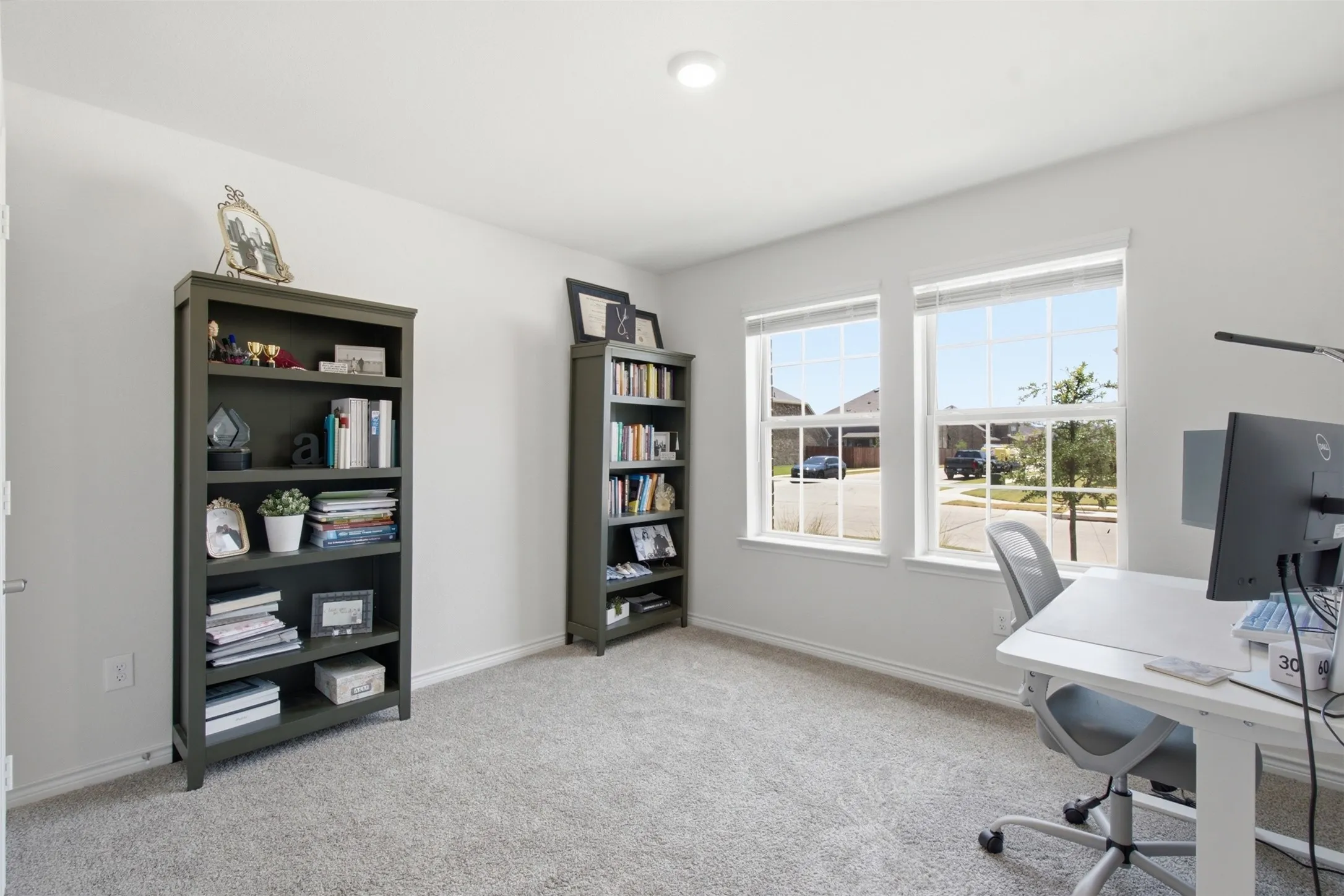 Bright room featuring two large windows with white blinds, grey carpet flooring, and white baseboards