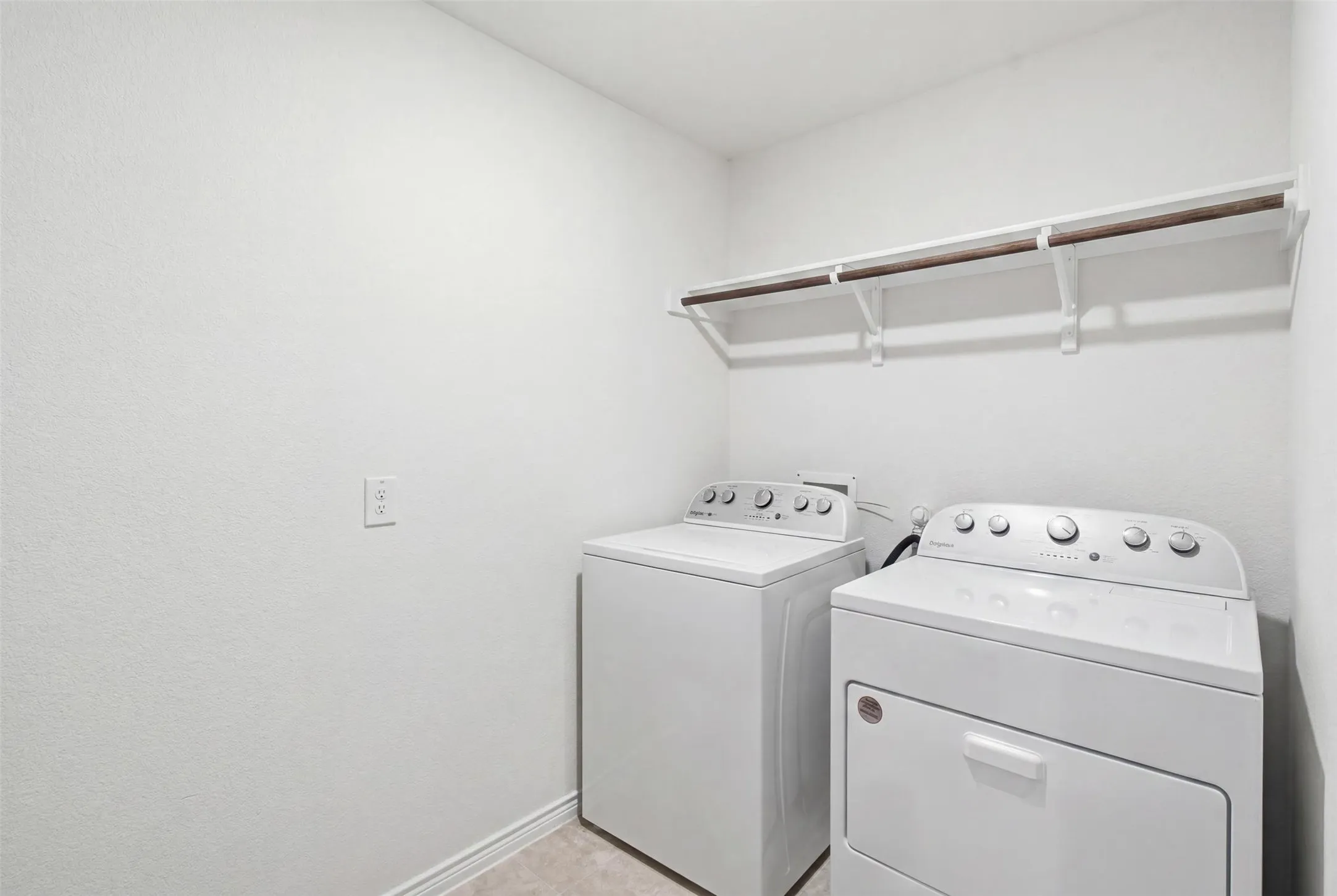 Dedicated utility space featuring a built-in hanging rod, wall-mounted shelving, and light-toned flooring
