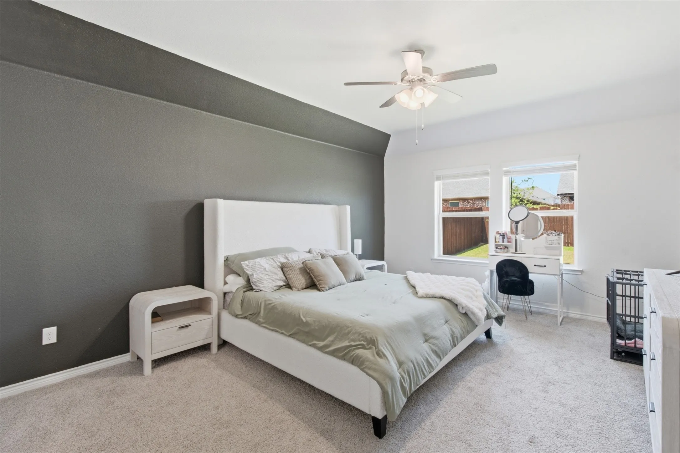Carpeted bedroom featuring a two-tone accent wall, dual windows, and a ceiling fan with integrated lighting