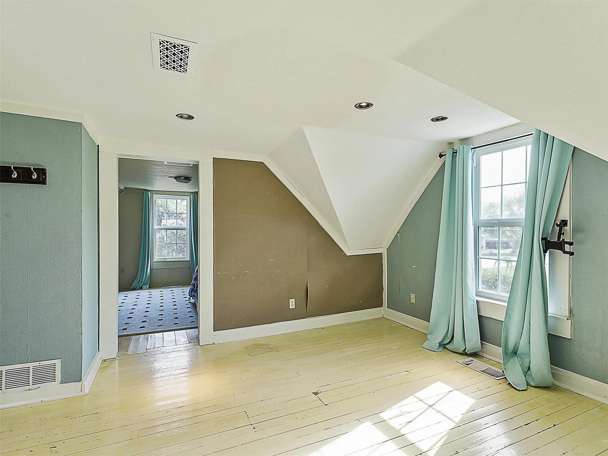 Room featuring painted wood-finish flooring, two window openings, recessed lighting, and a sloped ceiling design