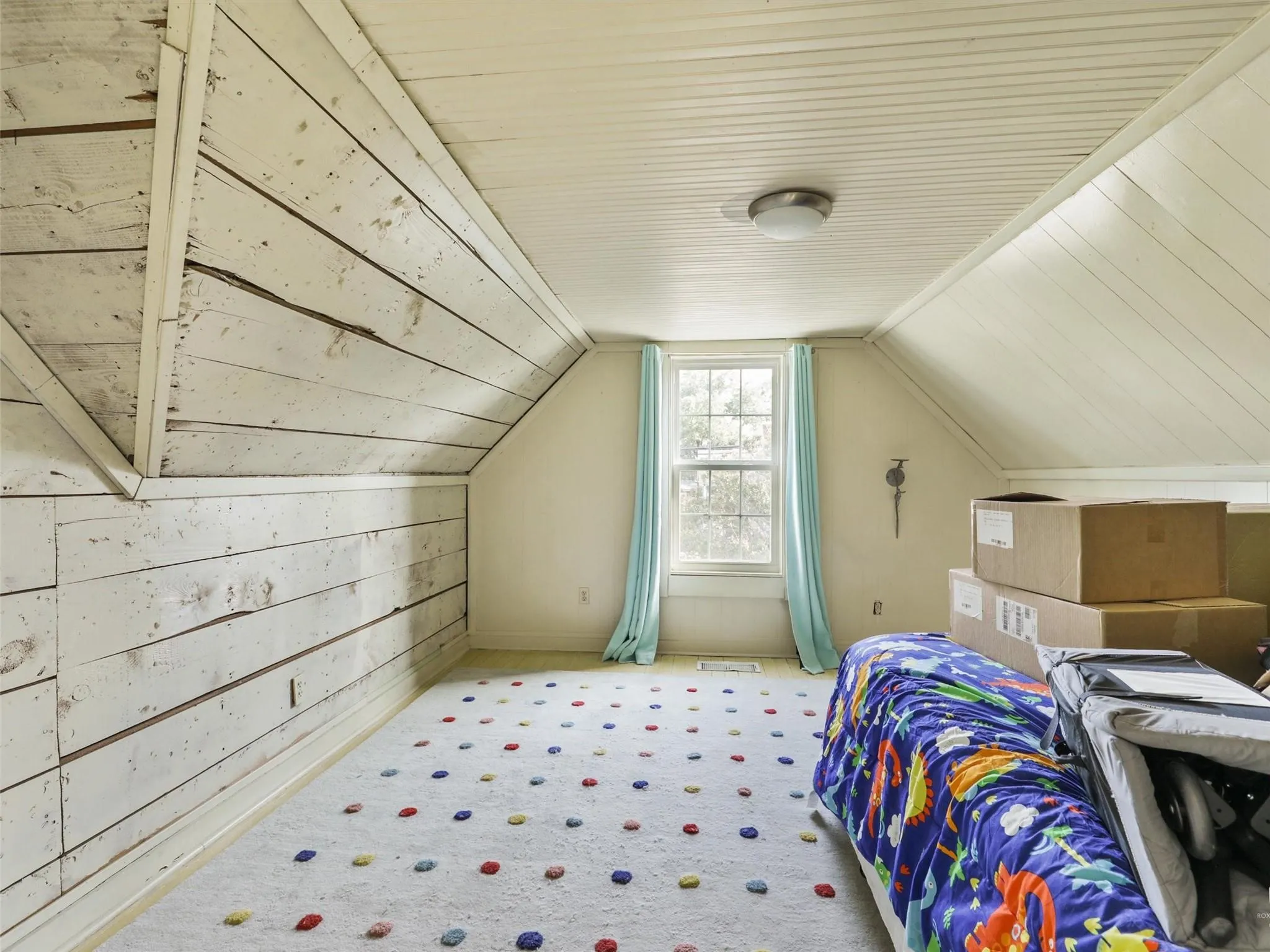 Attic space featuring sloped wood-paneled walls and a flat beadboard ceiling