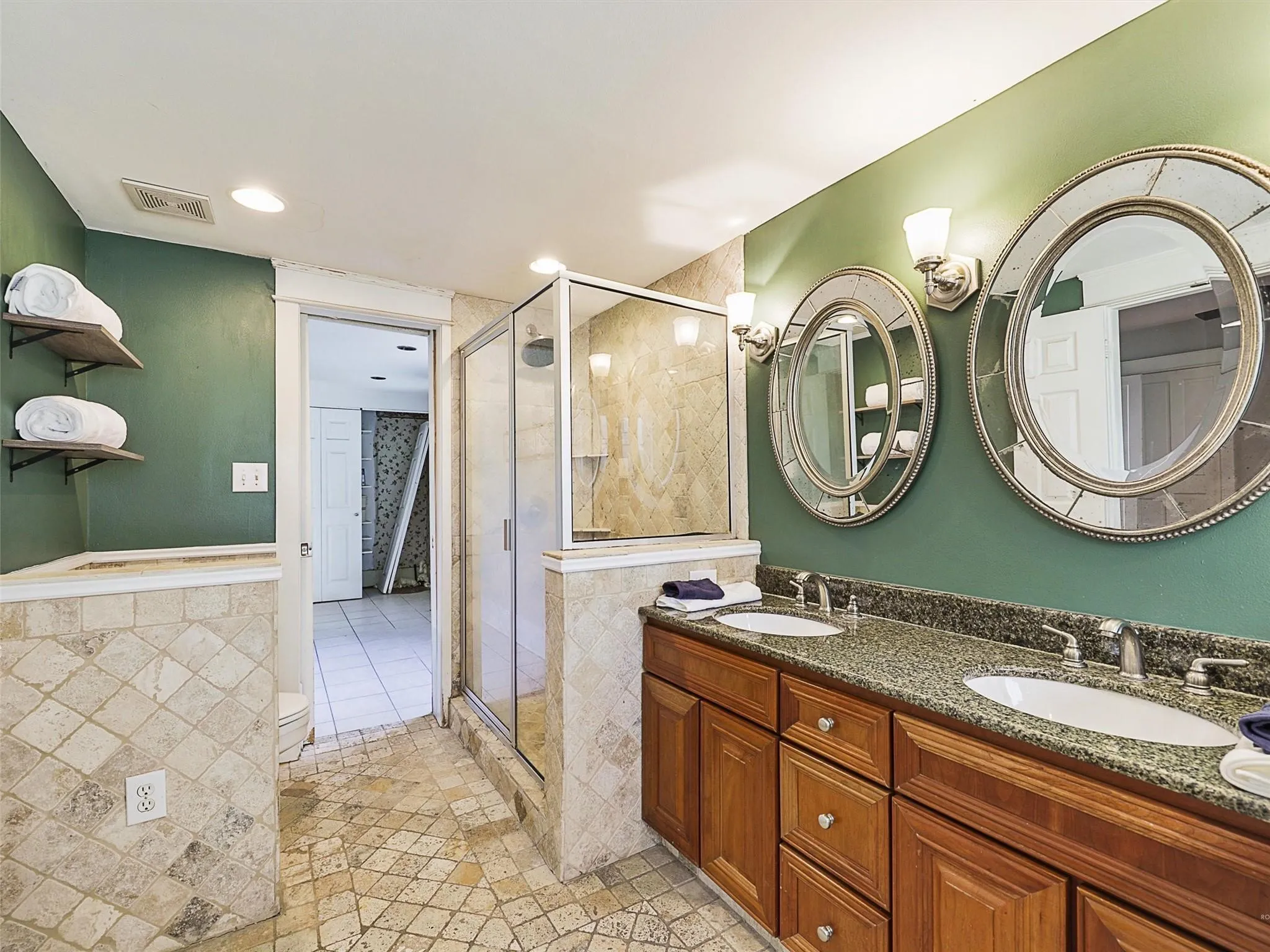 Bathroom featuring a double vanity with granite countertop, dual undermount sinks, and wood-finish cabinetry