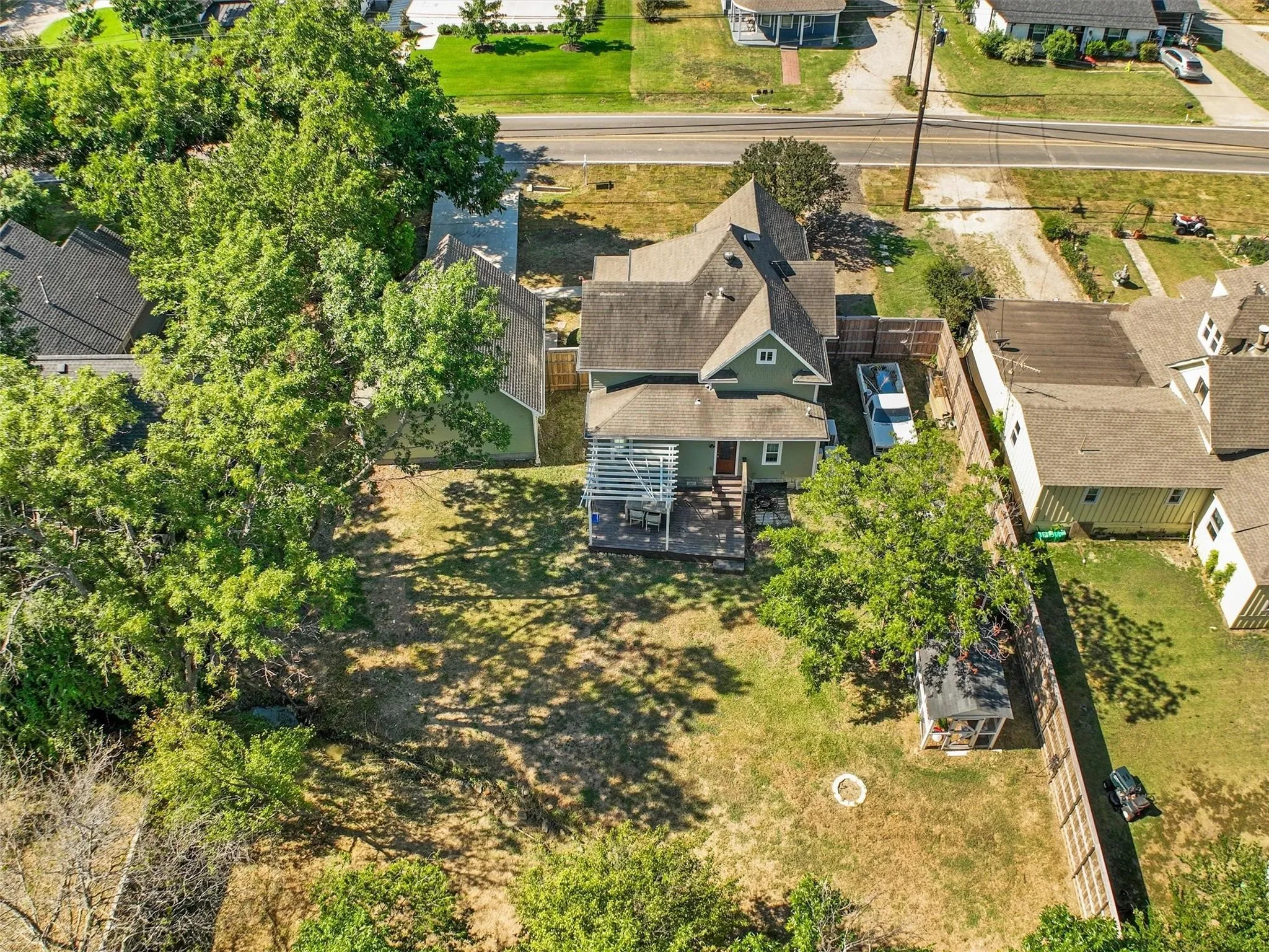 Expansive property featuring a green-sided residence with multiple gabled rooflines, a large backyard with a gazebo, mature trees, and a wooden privacy fence