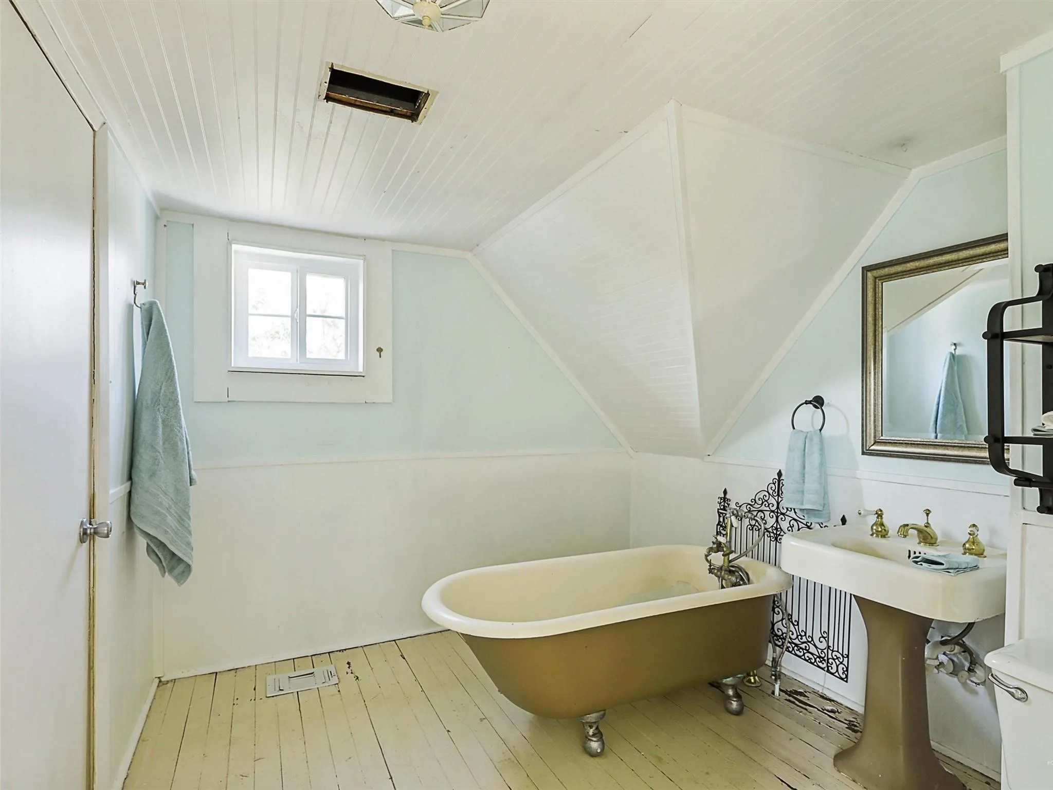 Bathroom featuring a freestanding clawfoot tub, pedestal sink with brass-finish fixtures, paneled ceiling, and a sash window