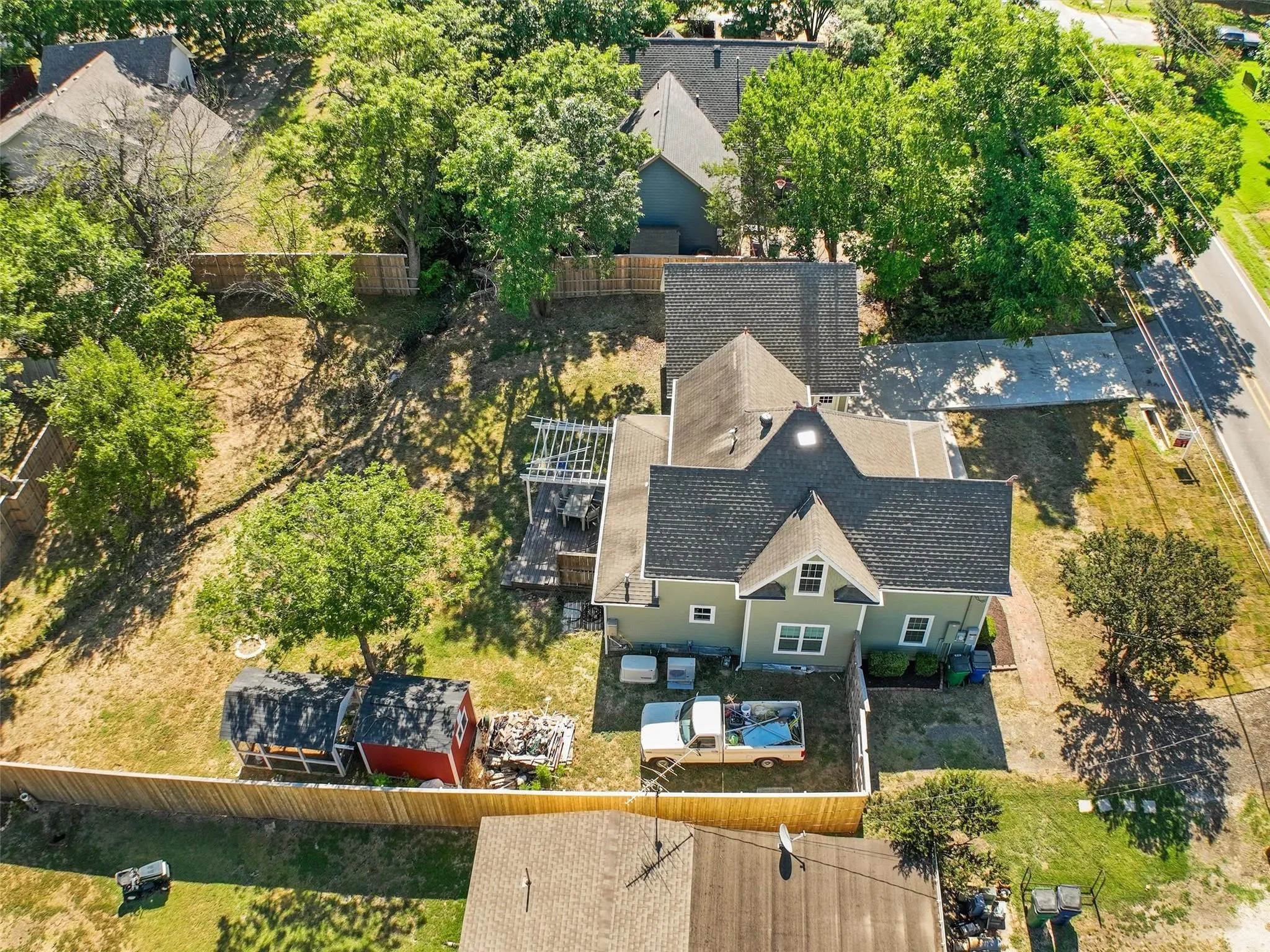 Property featuring a sage green exterior with white trim, dark shingle roof, and a rear deck with a pergola