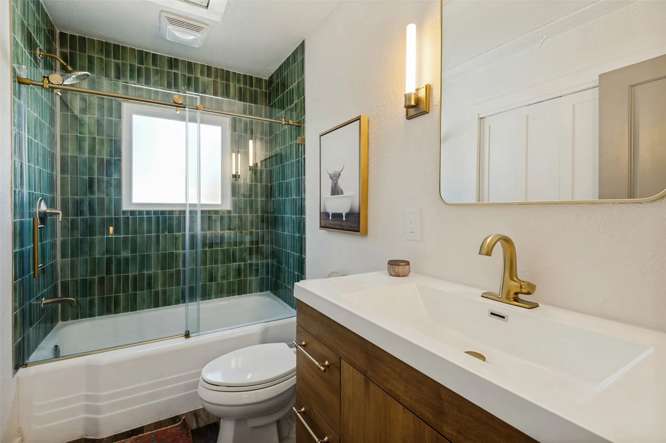 Updated bathroom with tub and shower, also houses washer and dryer in enclosed closet. Wood vanity, brass fixtures.
