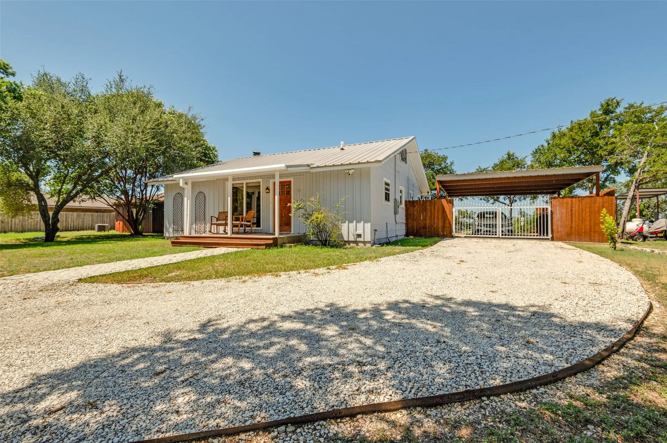 Gravel circular drive to road and gated carport.