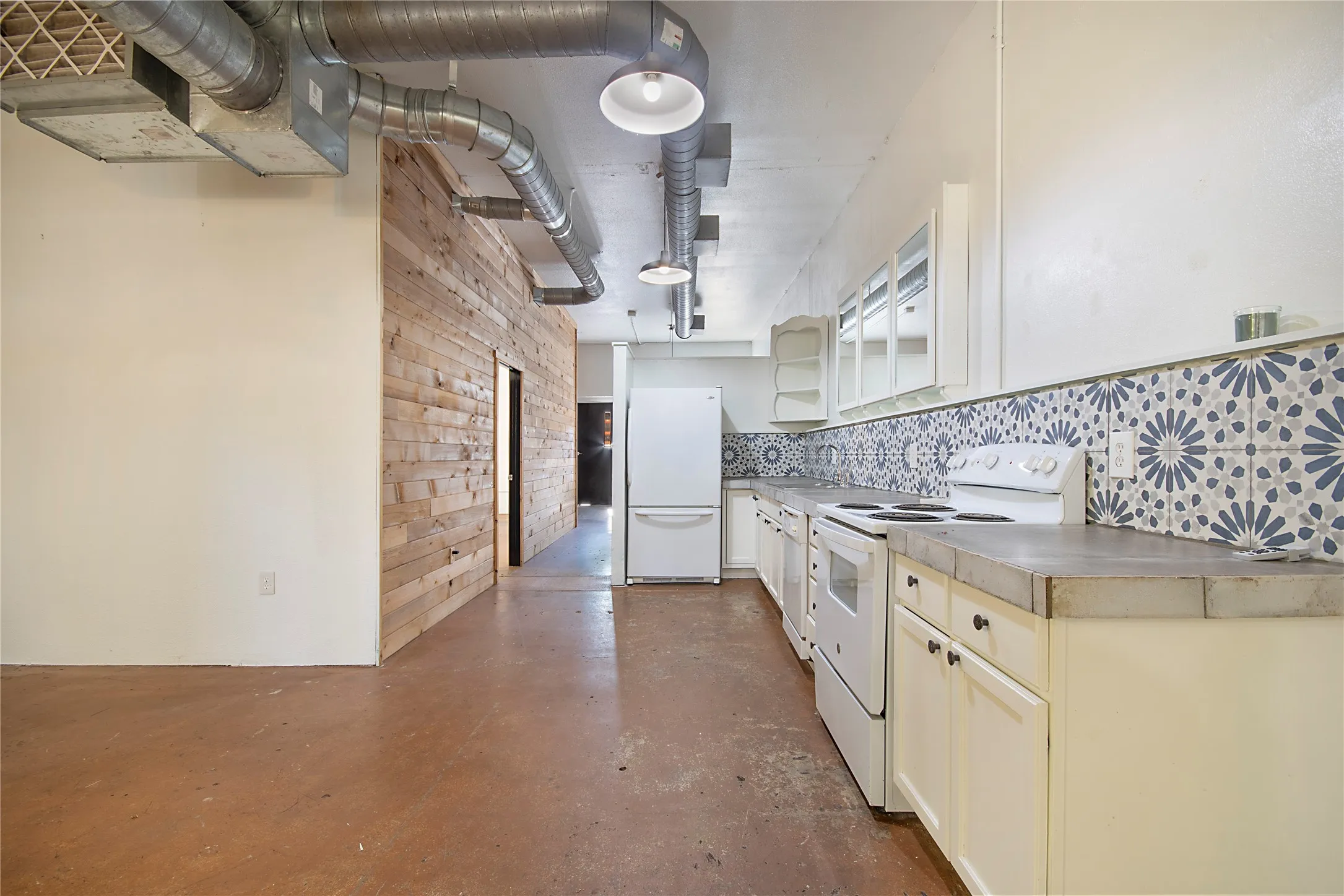 Kitchen with exposed ductwork, concrete-finish flooring, and a decorative tile backsplash