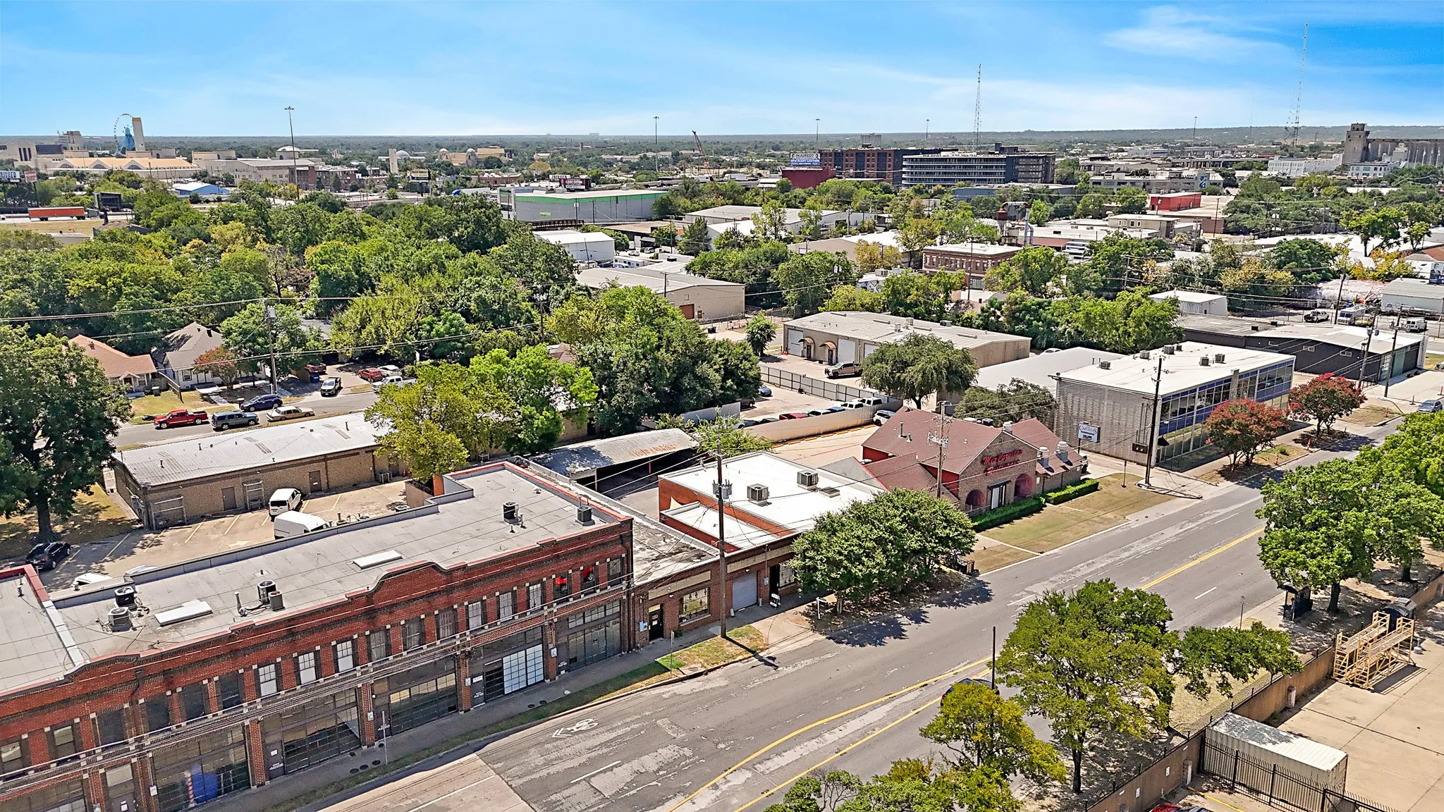 Urban landscape featuring a prominent brick commercial building with multiple window bays, a flat roof, and an expansive paved area
