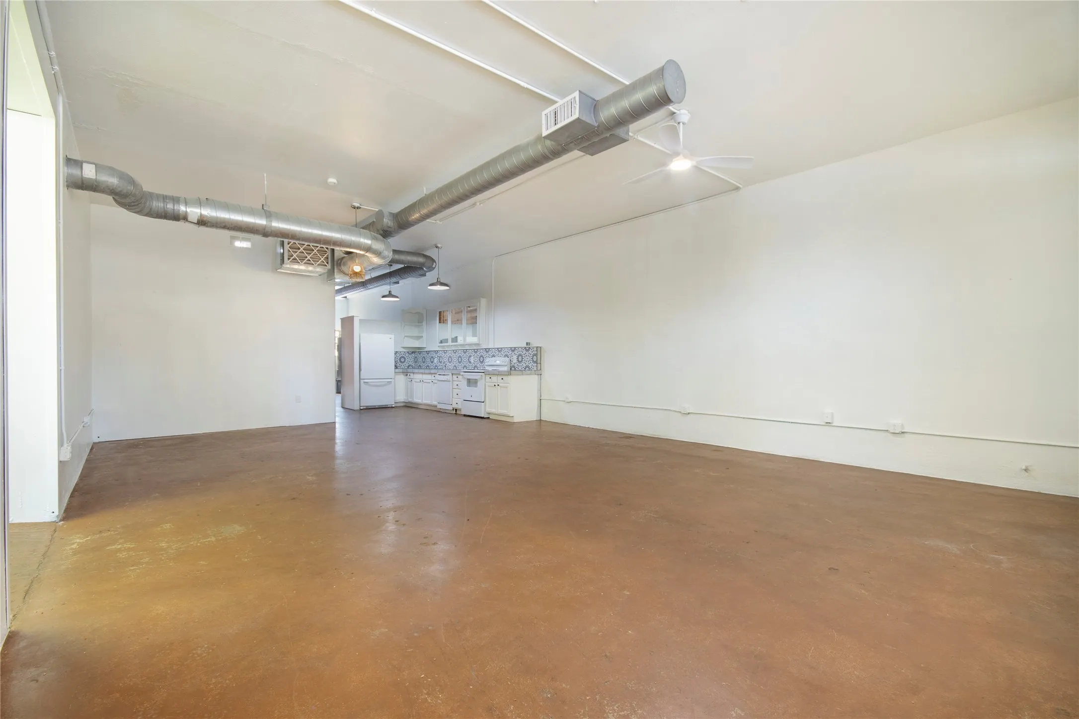 Expansive open-concept space featuring concrete flooring, exposed overhead ductwork, and high ceilings