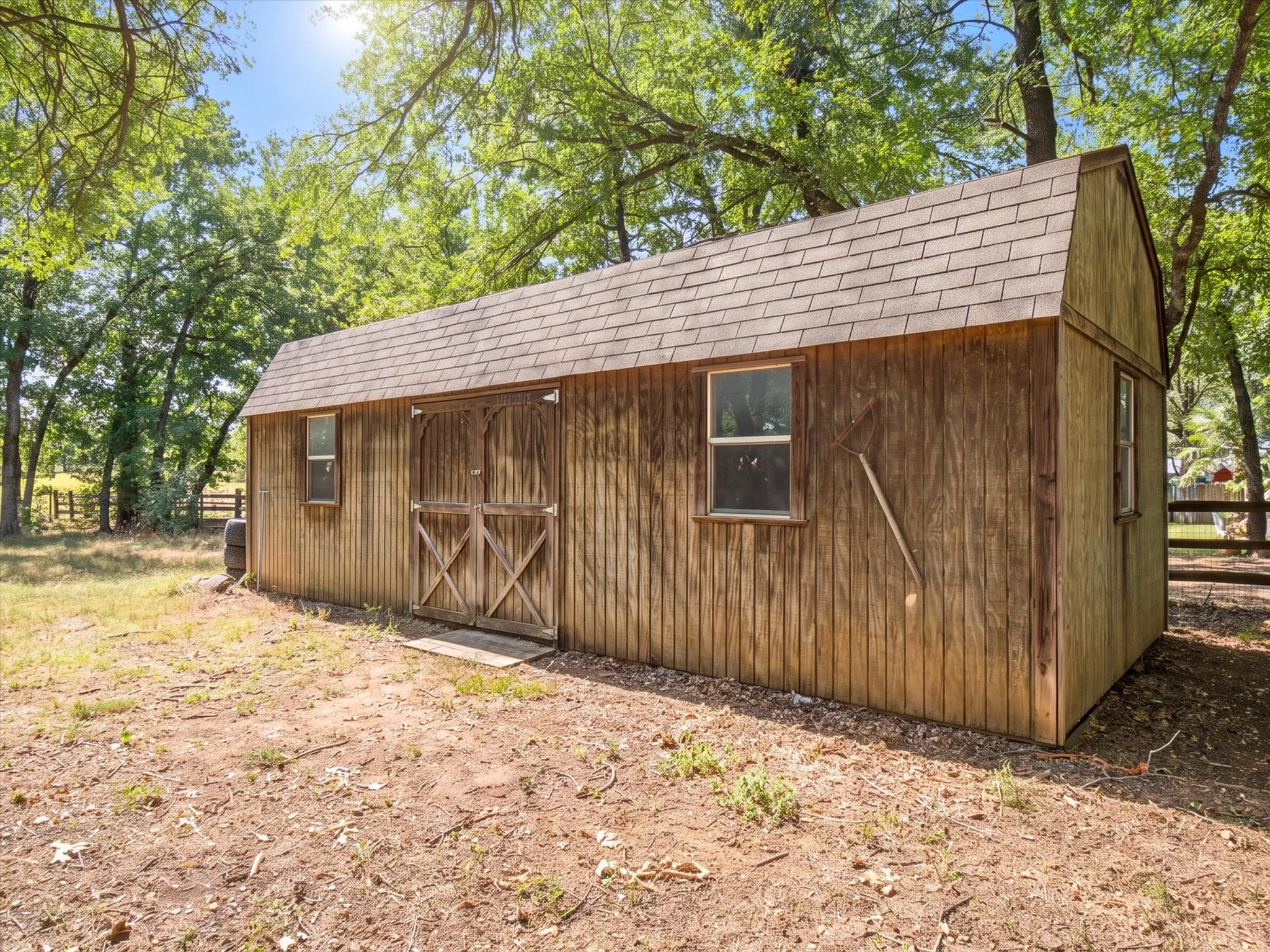Wood-sided outbuilding featuring a gambrel roof and double barn doors