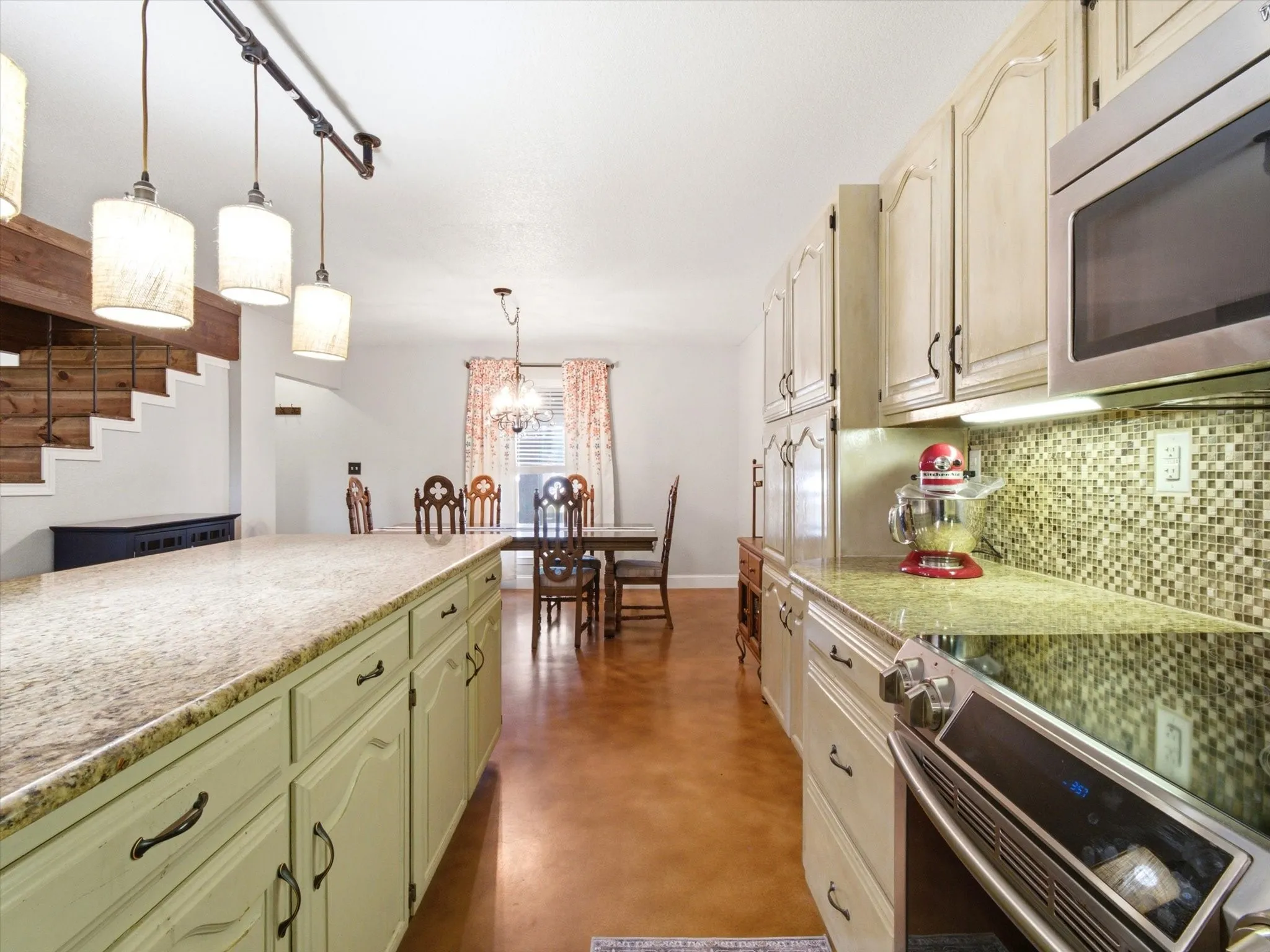 Kitchen featuring light-toned cabinetry, stainless steel appliances, mosaic tile backsplash, stone countertops, and wood-finish flooring