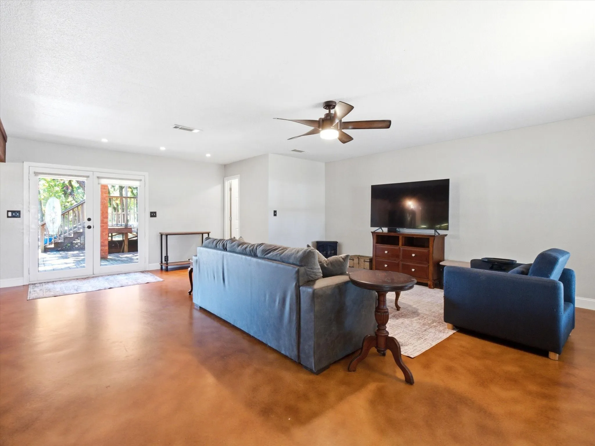 Spacious living area featuring rich brown-toned flooring and white walls