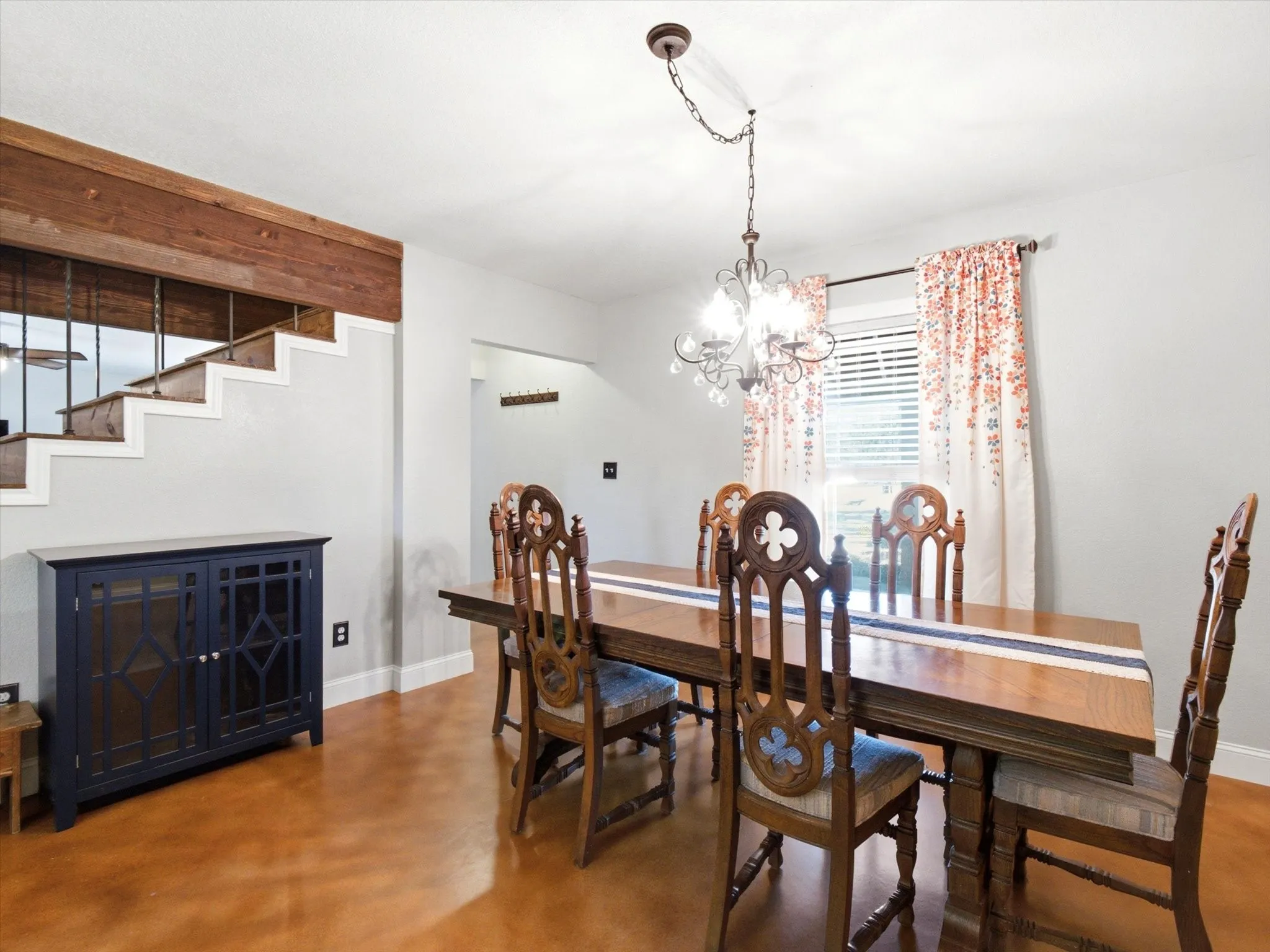 Formal dining area featuring a decorative chandelier, wood-finish flooring, and natural light from a window with blinds