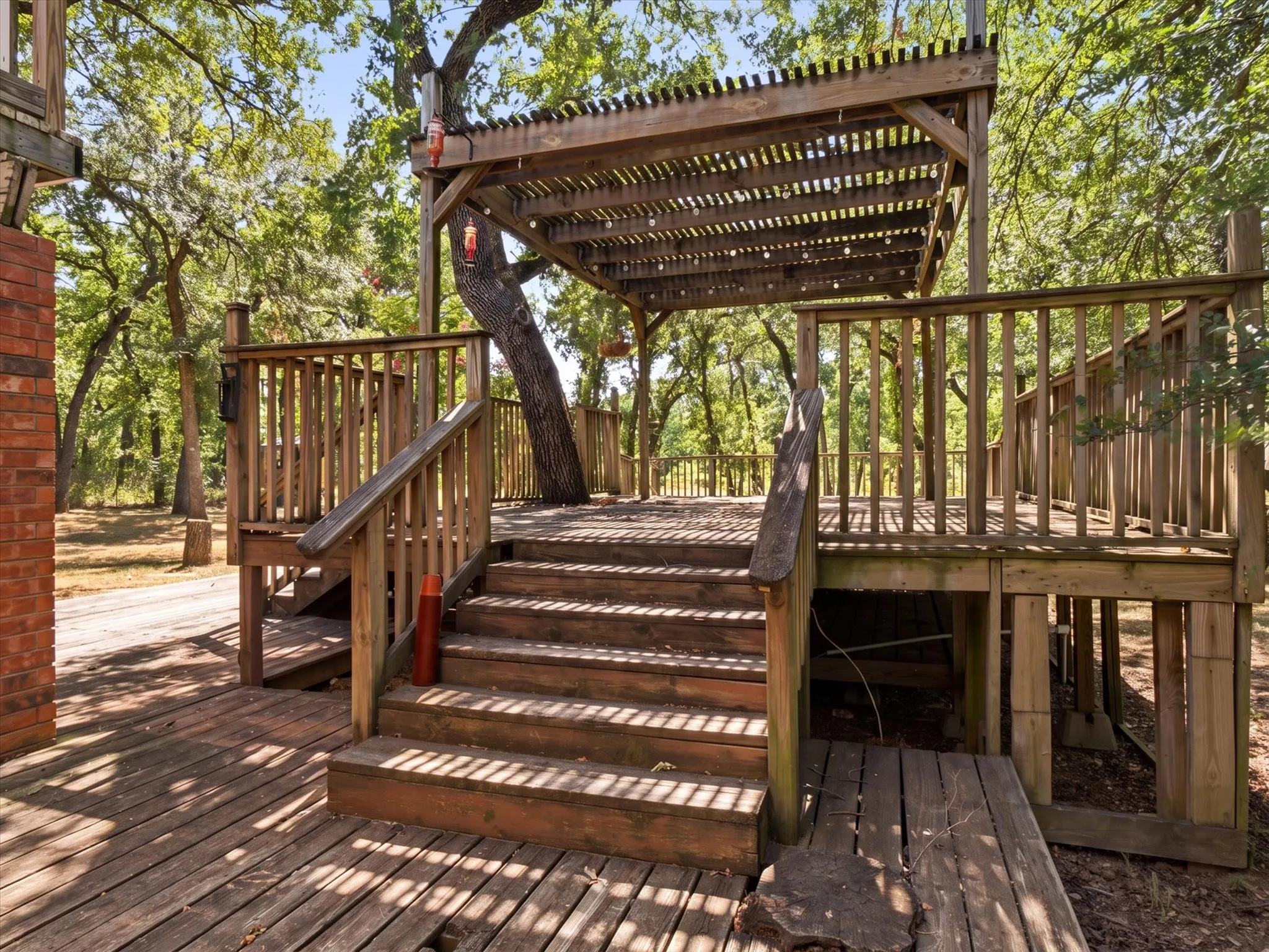 Expansive wood deck featuring a slatted pergola, integrated staircase, and sturdy wood railings