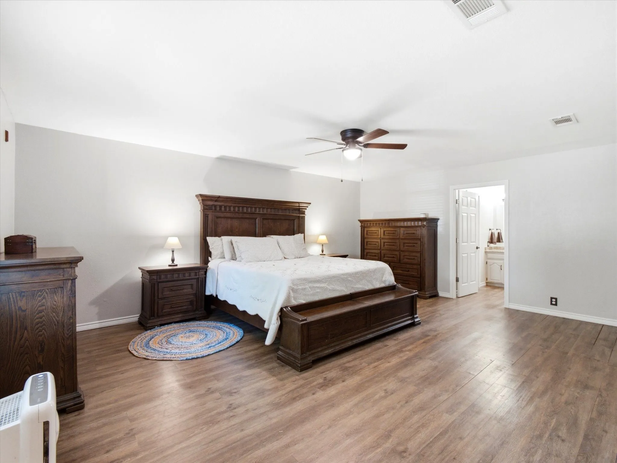 Spacious room featuring wood-finish flooring, light gray walls, and a ceiling fan with light fixture