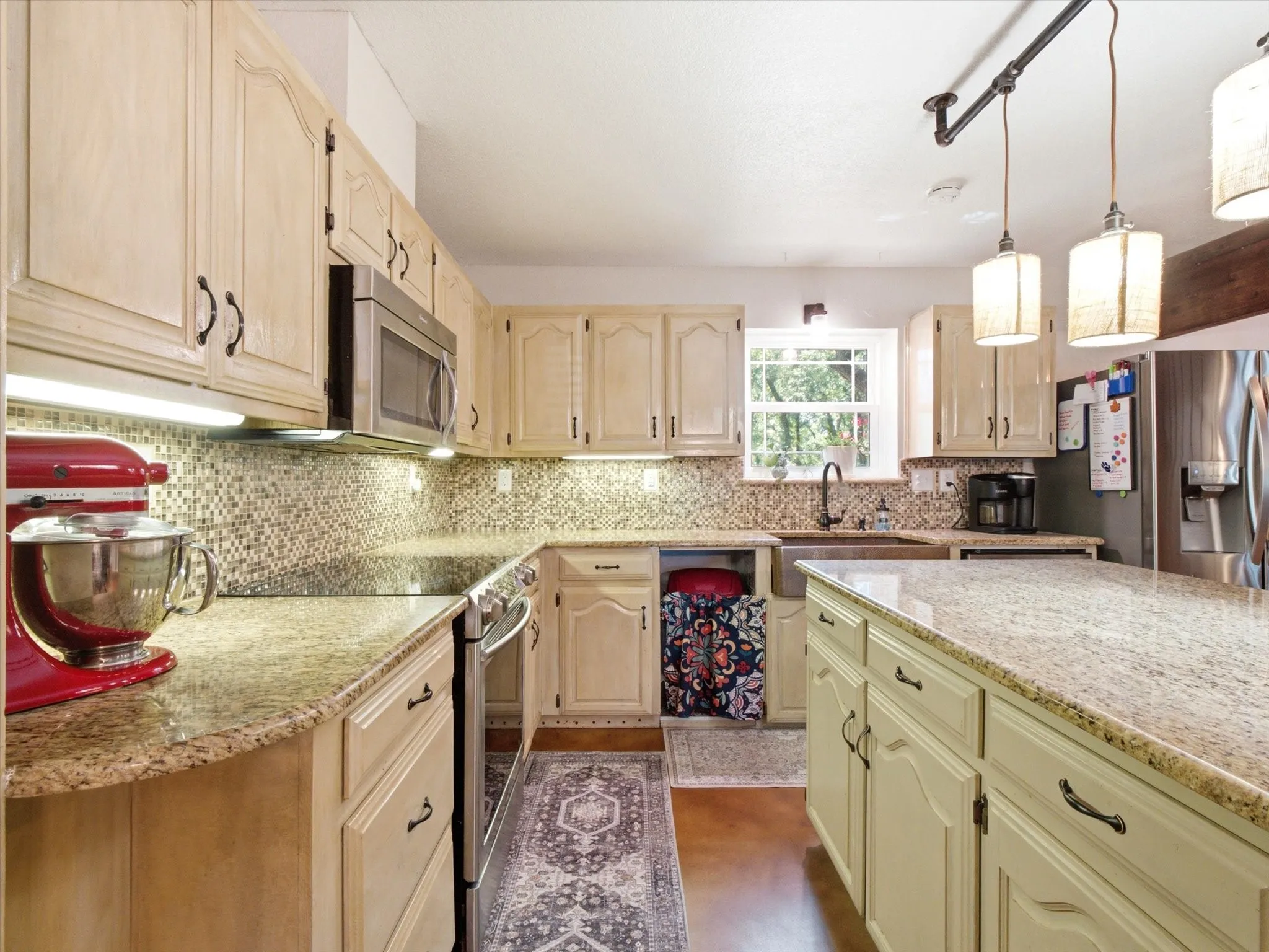 Kitchen featuring light-toned cabinetry, granite countertops, and a mosaic tile backsplash