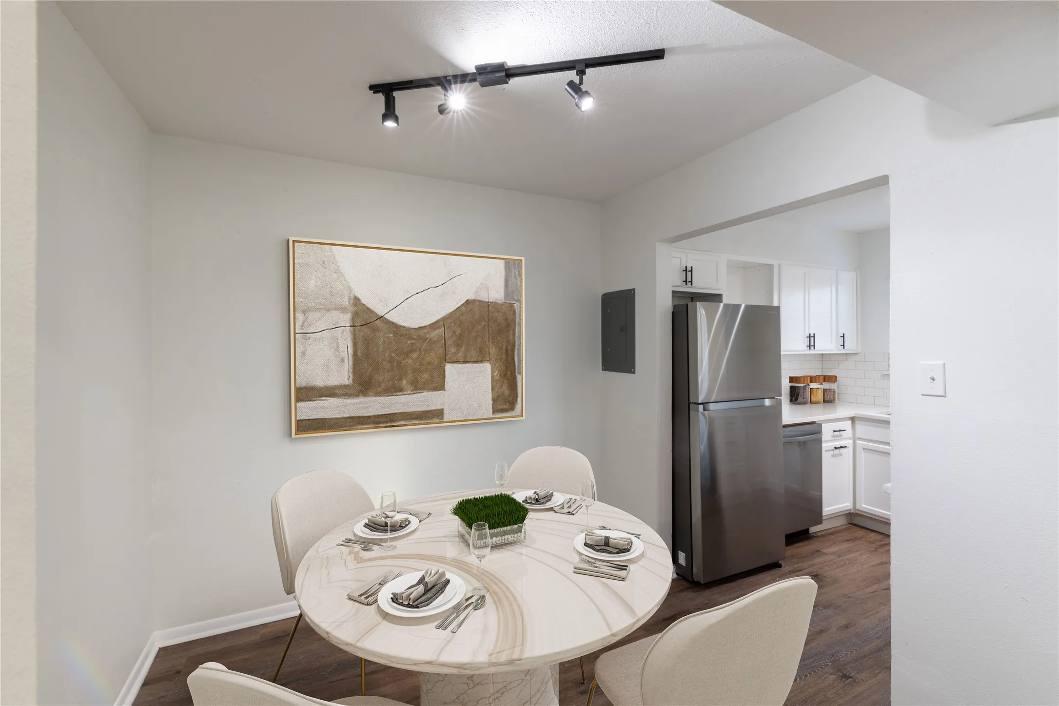 Dining area with wood-finish flooring, track lighting, and a partial view of the kitchen