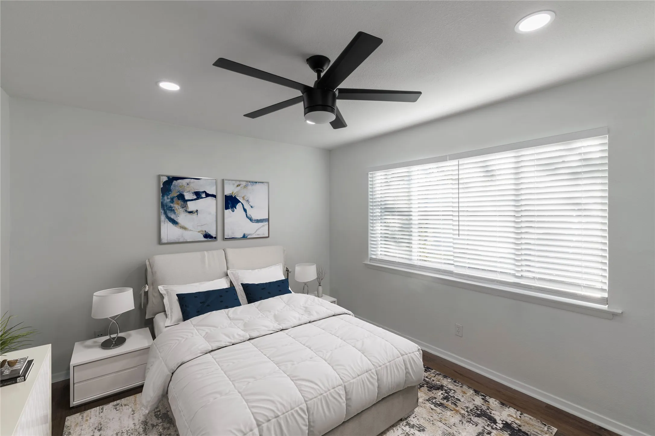 Recessed ceiling lighting, a modern ceiling fan, and wood-finish flooring define this room