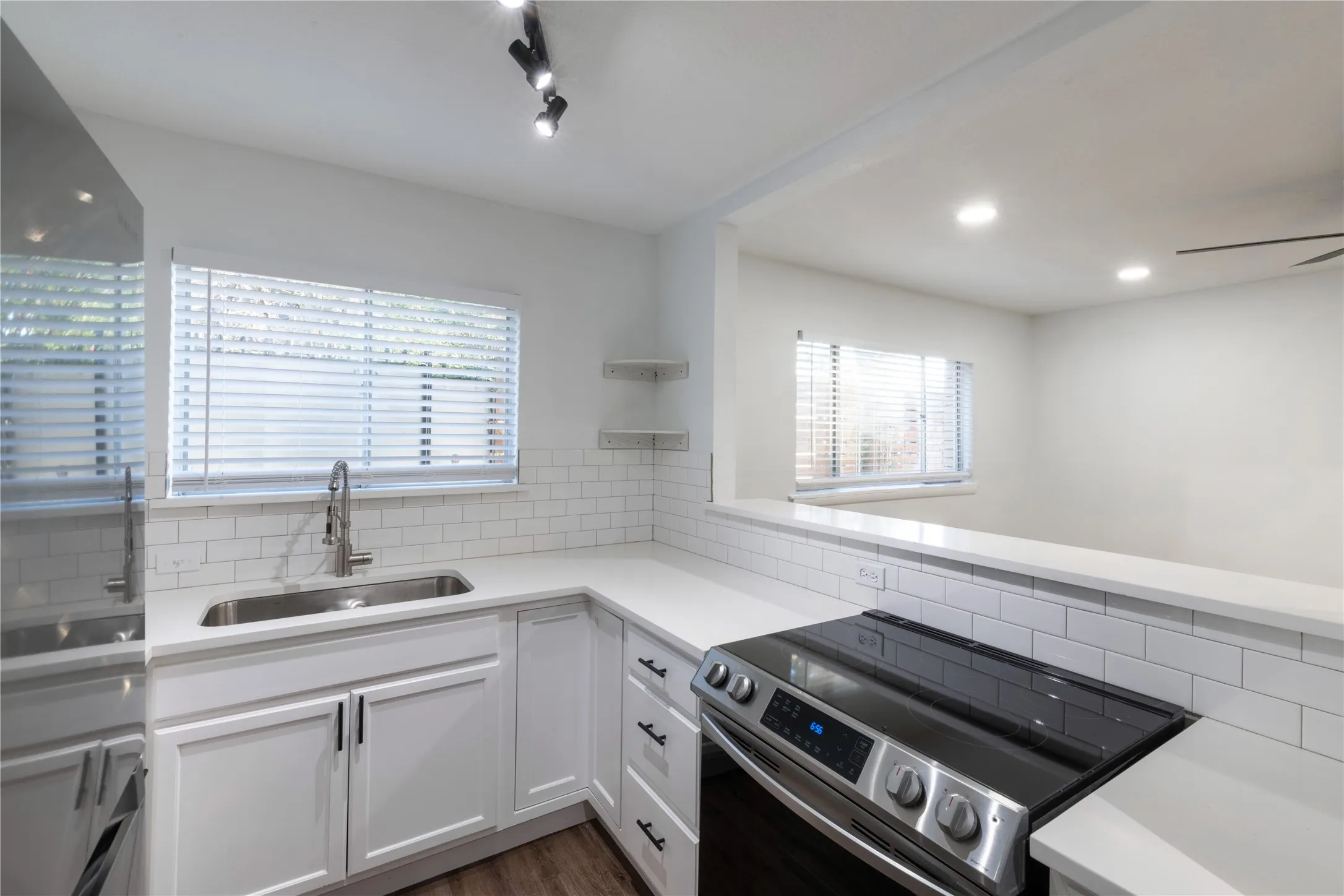 Modern kitchen featuring white shaker cabinetry, white countertops, a stainless steel sink with a gooseneck faucet, a subway tile backsplash, and a built-in electric range